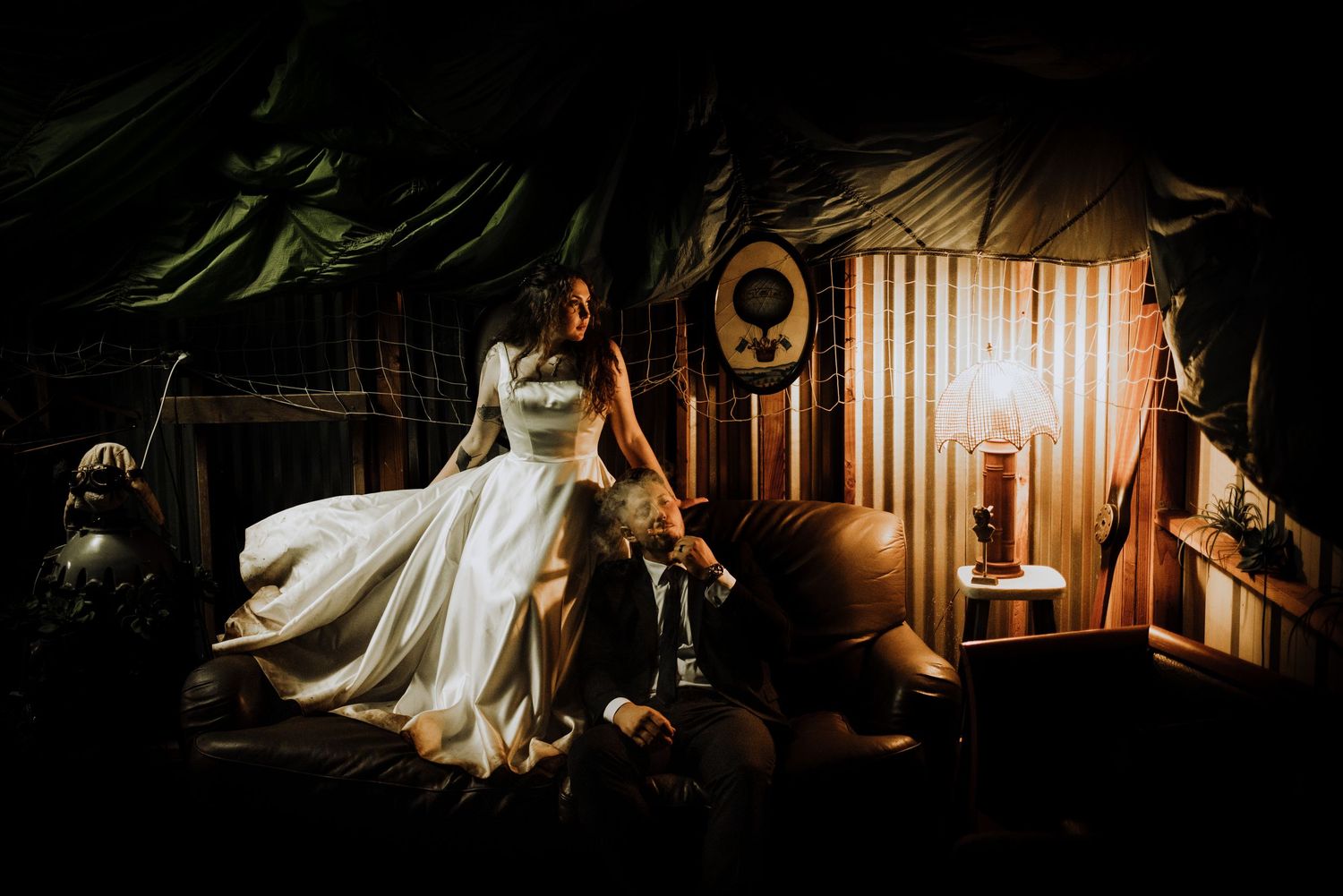 Wedding couple poses in dramatic low-light setting with artistic shadows and highlights.