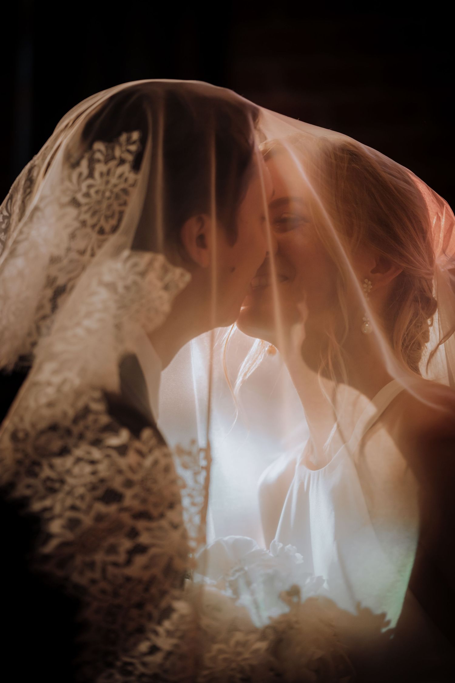 Ethereal close-up of white lace wedding dress details in soft lighting.