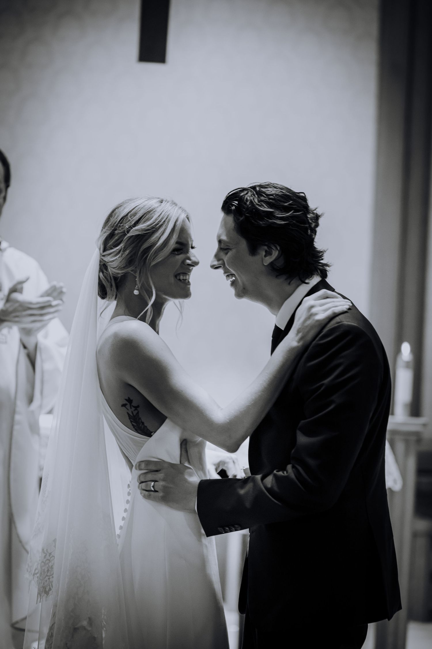 A tender moment between newlyweds sharing a laugh in black and white.