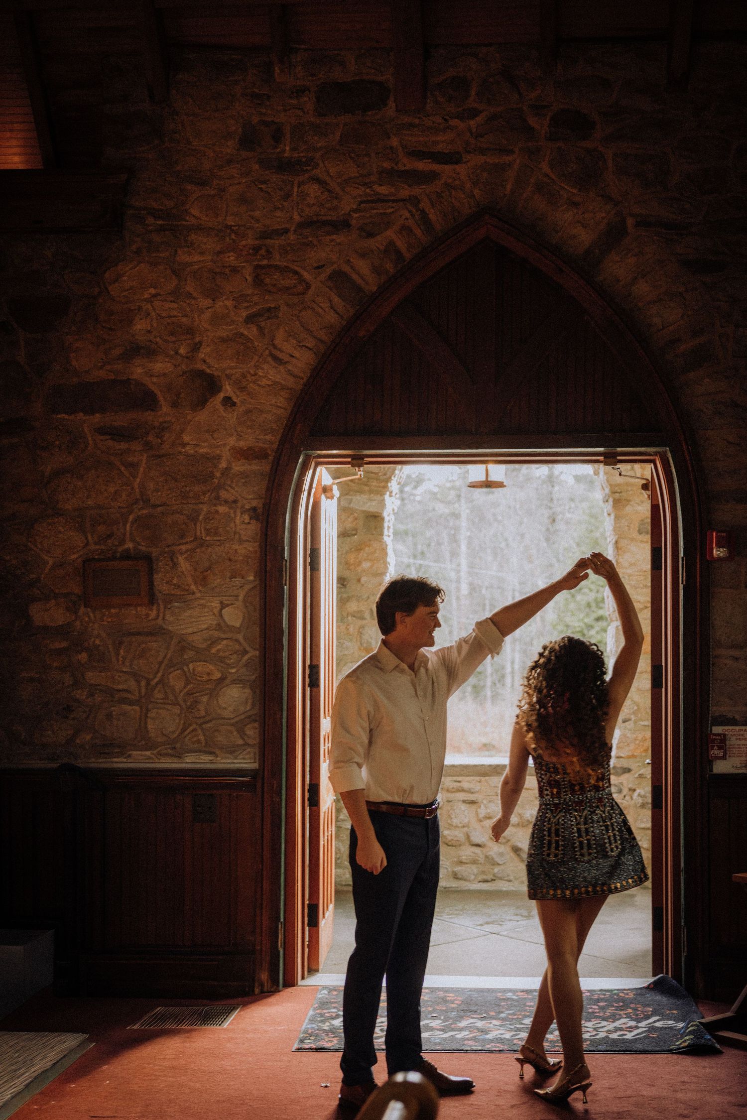 A couple dancing in silhouette against a bright doorway in a stone building.