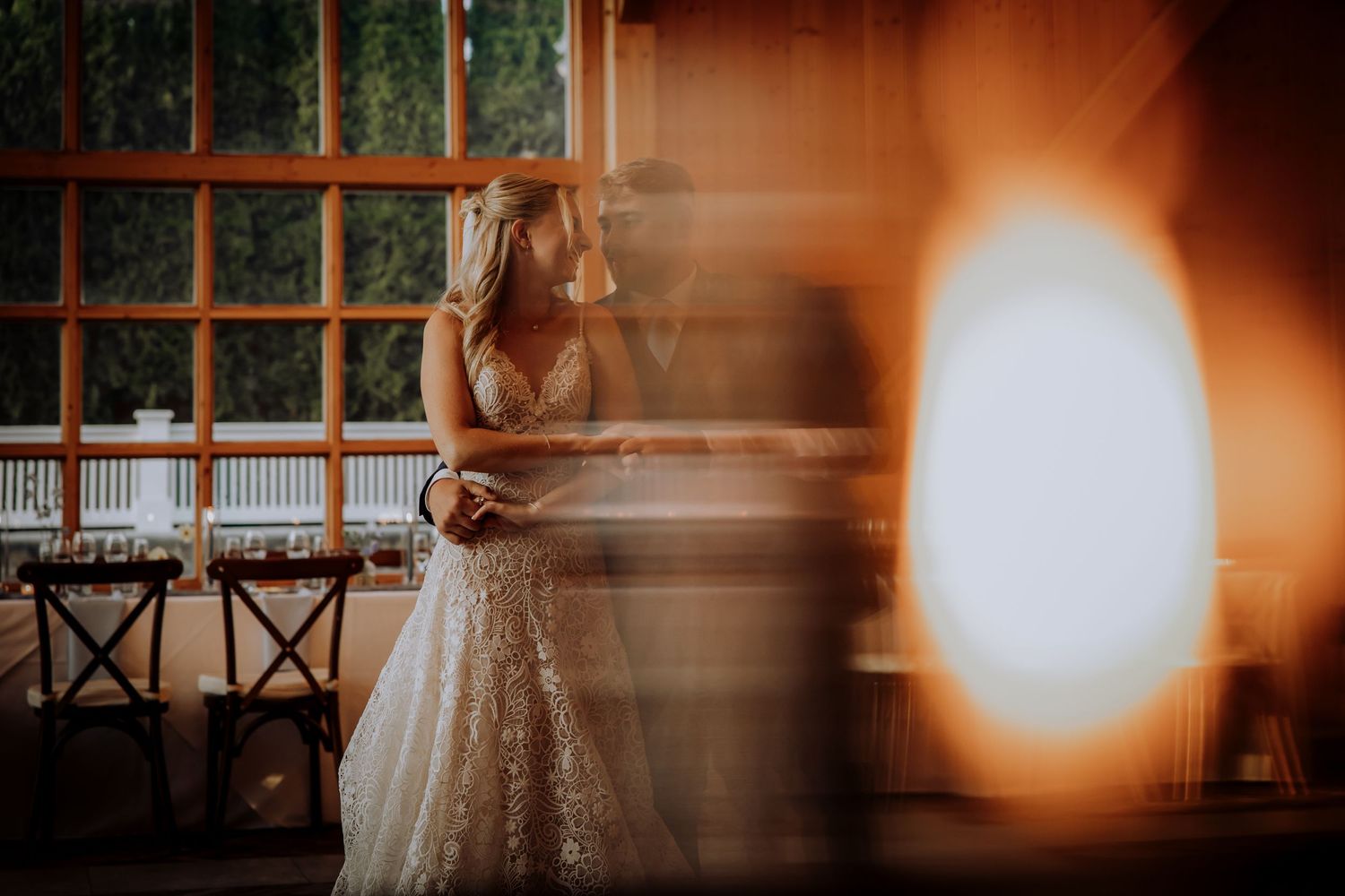 Artistic wedding photo with sunflare and warm tones in venue with large windows.Editorial and Cinematic Wedding photos