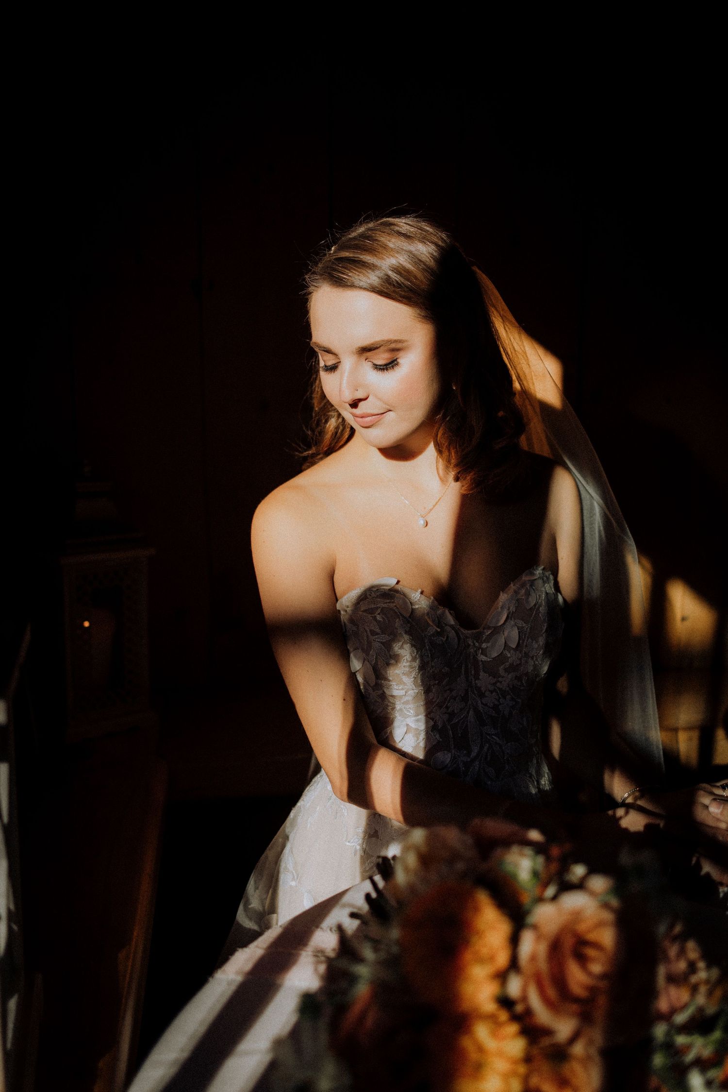 A close-up artistic portrait of a bride in a lace wedding dress with dramatic lighting.