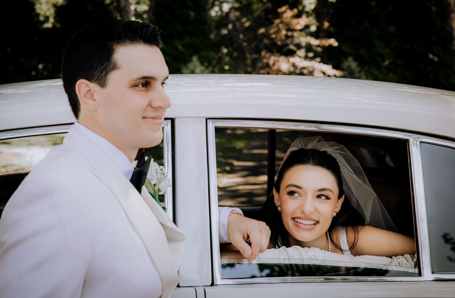 Wedding day moments captured through the window of a vintage automobile.