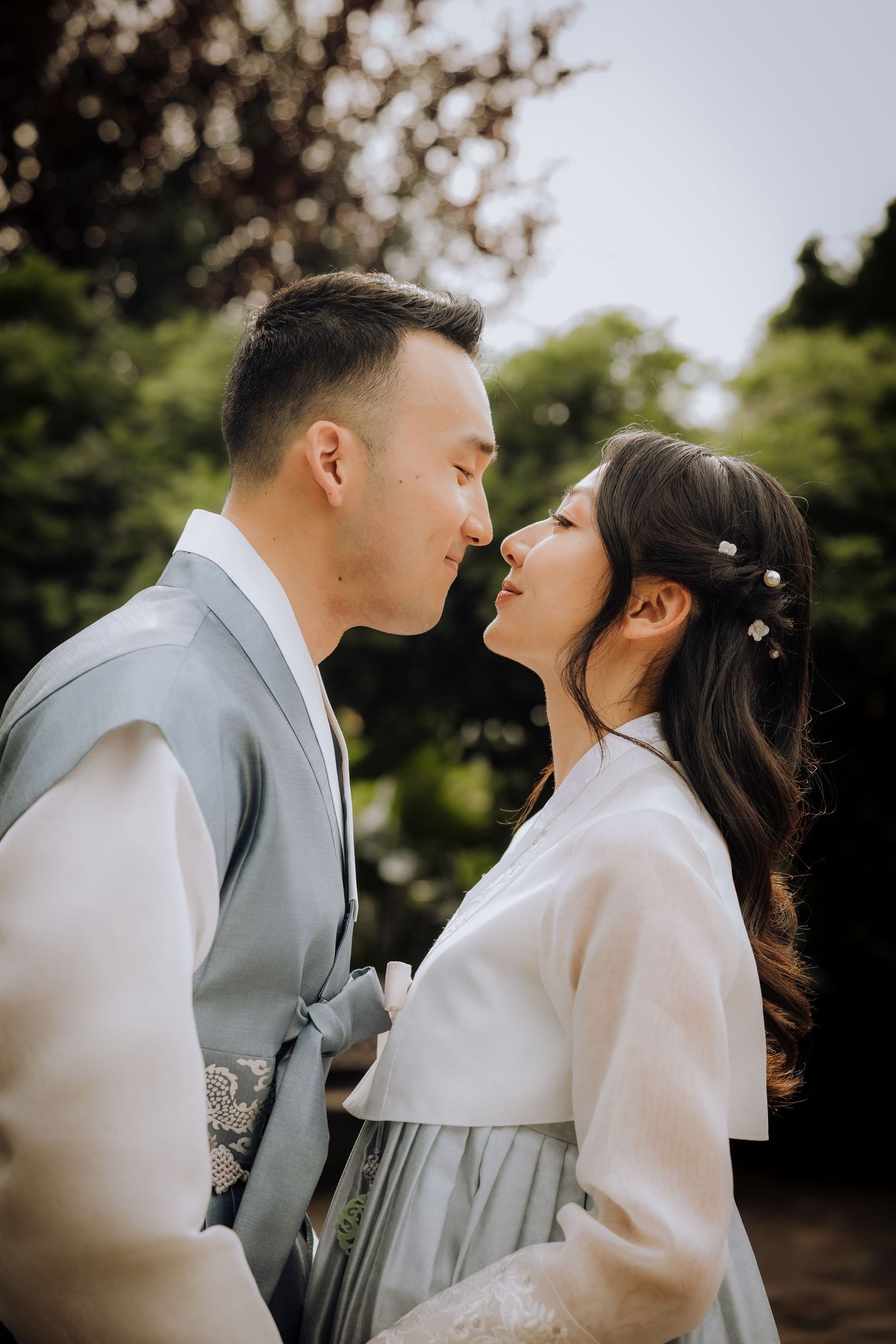 Romantic outdoor wedding portrait with soft natural lighting and blossoming trees.