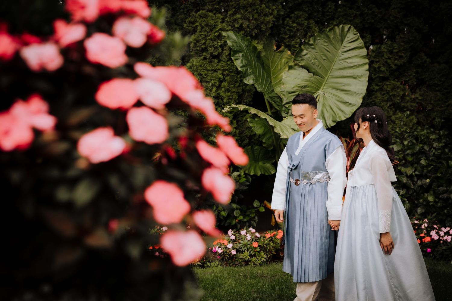 A romantic garden wedding photoshoot with pink cherry blossoms and greenery in the background.