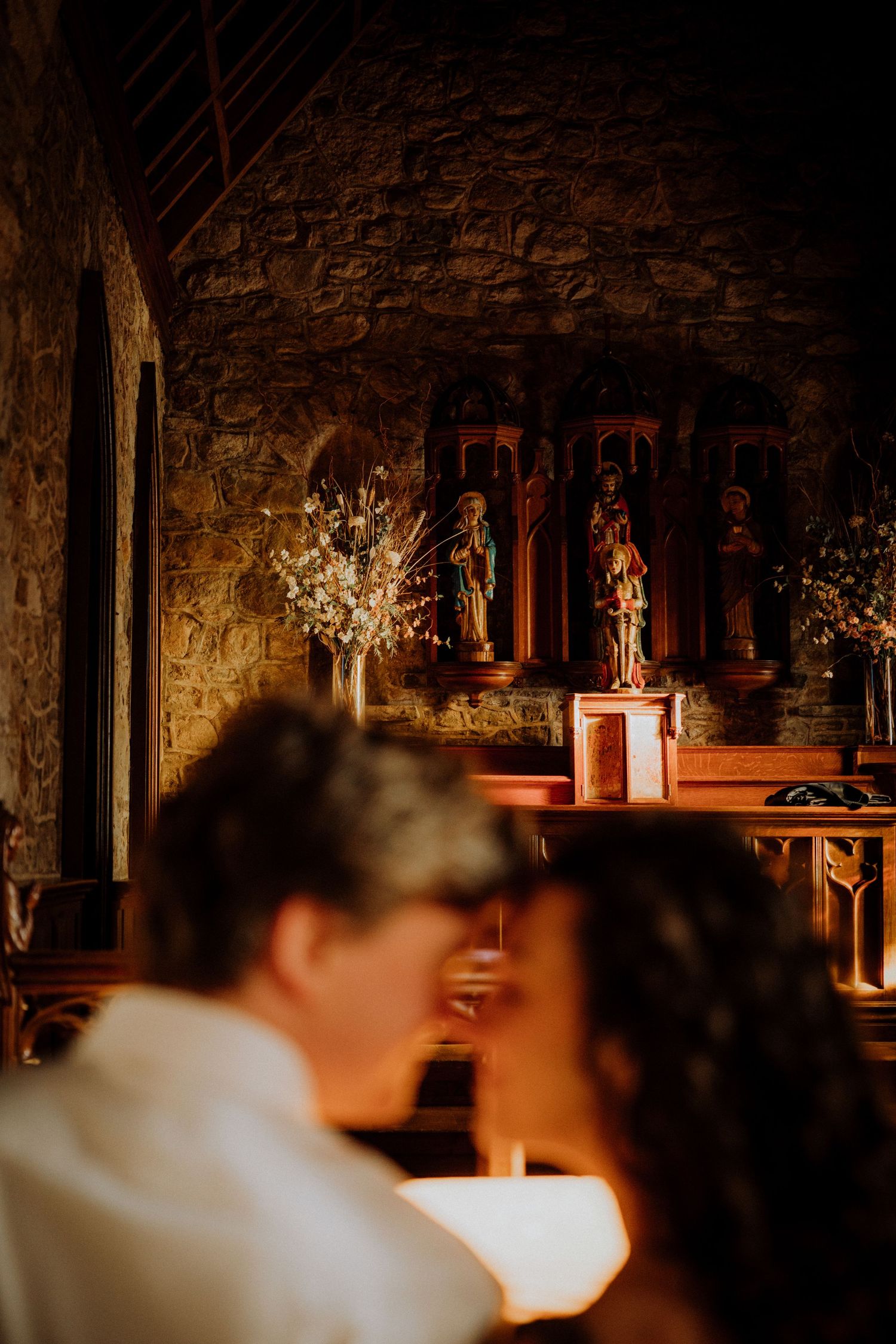 Romantic moment captured in church with stone walls and altar decorations visible in warm lighting.