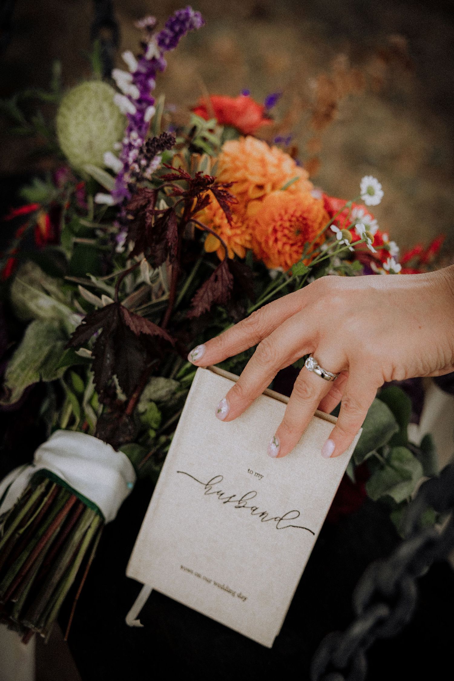 Wedding invitation cards displayed among orange and purple autumn flowers.
