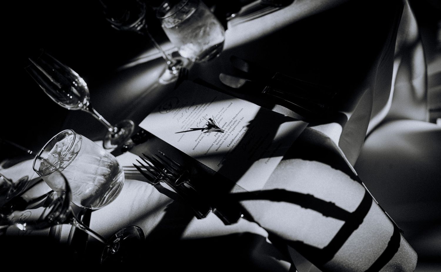 Elegant black and white detail shot of table settings at a formal dinner event.