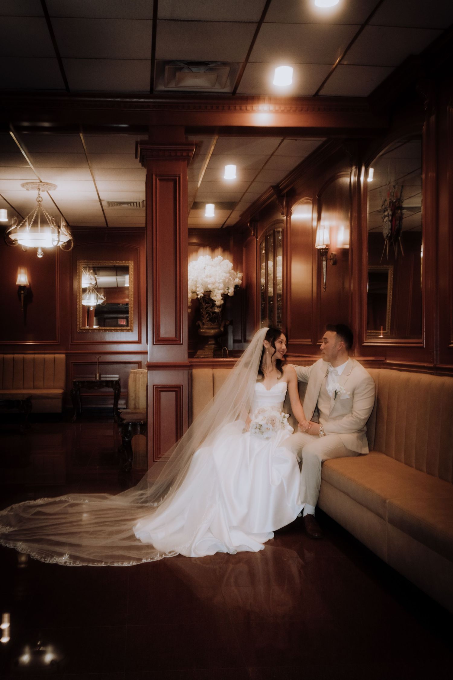 Wedding couple poses dramatically in wood-paneled hallway with elegant lighting.