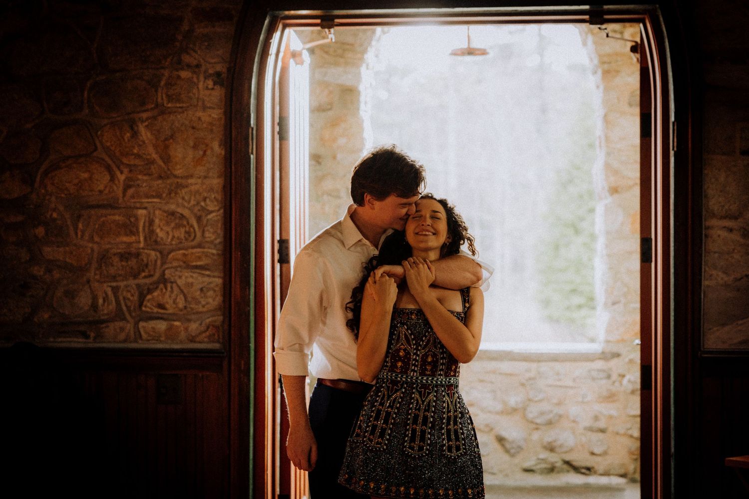 Couple sharing intimate moments in a rustic room with natural window light.