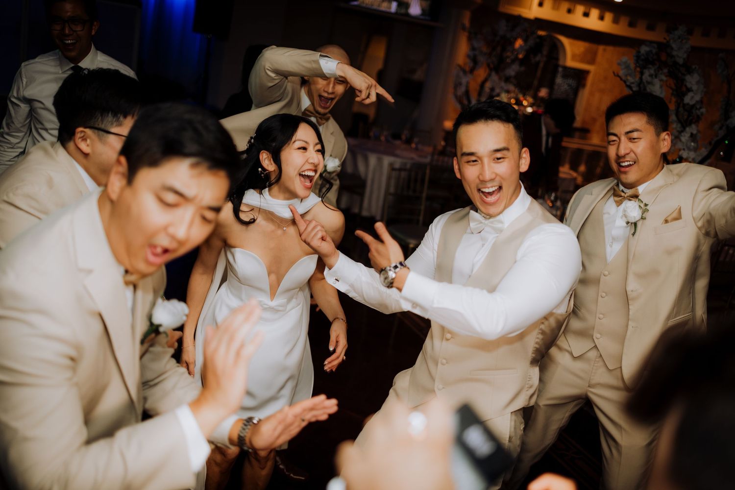 Energetic dance party scene with guests in formal attire at wedding reception.