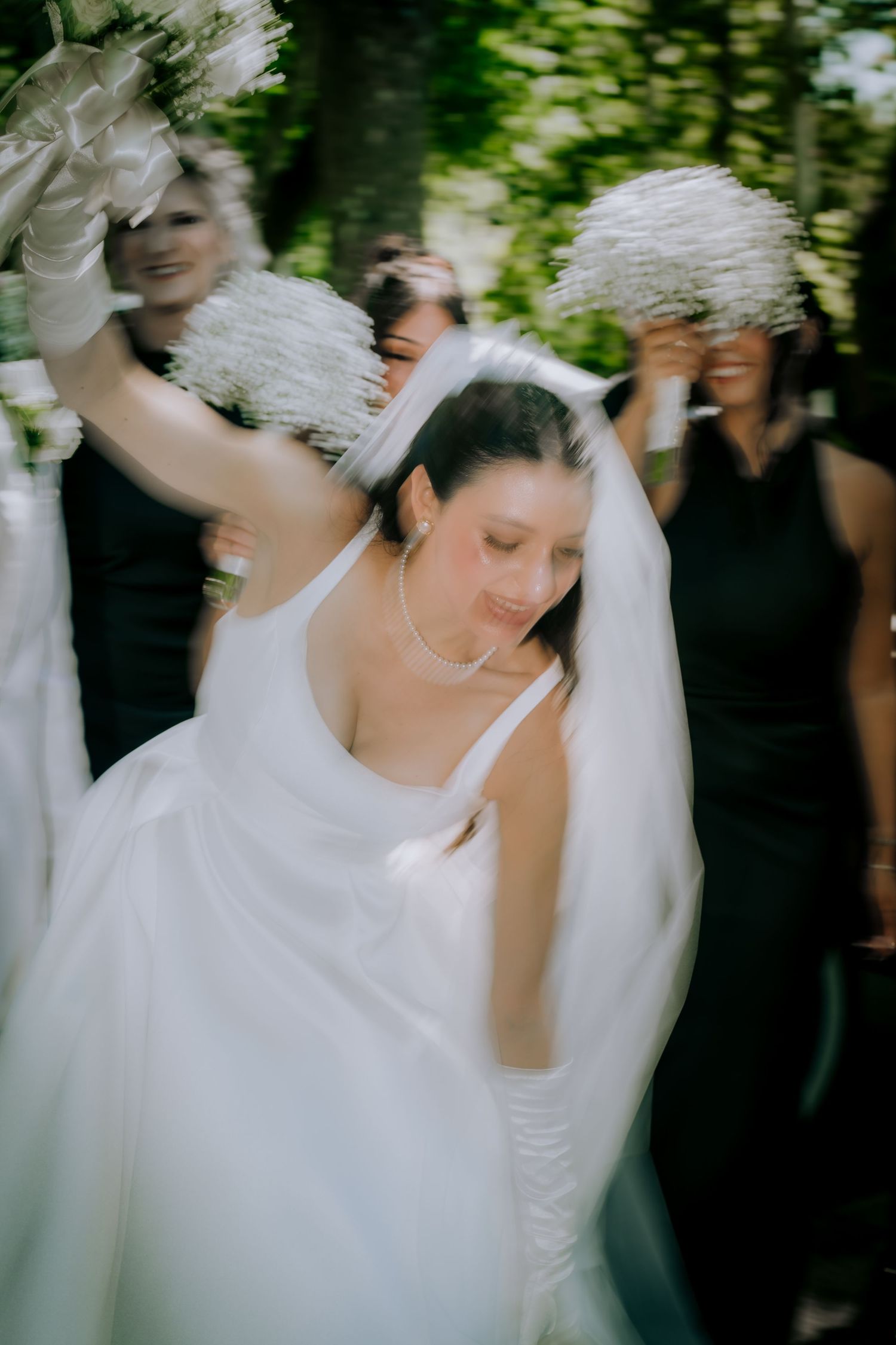 Ethereal bridal portrait with flowing veil and white dress in garden setting.