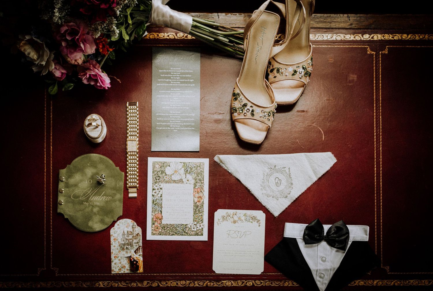 Wedding flat lay with gold heels, floral invitations, bouquet, and bow tie details on a red surface.