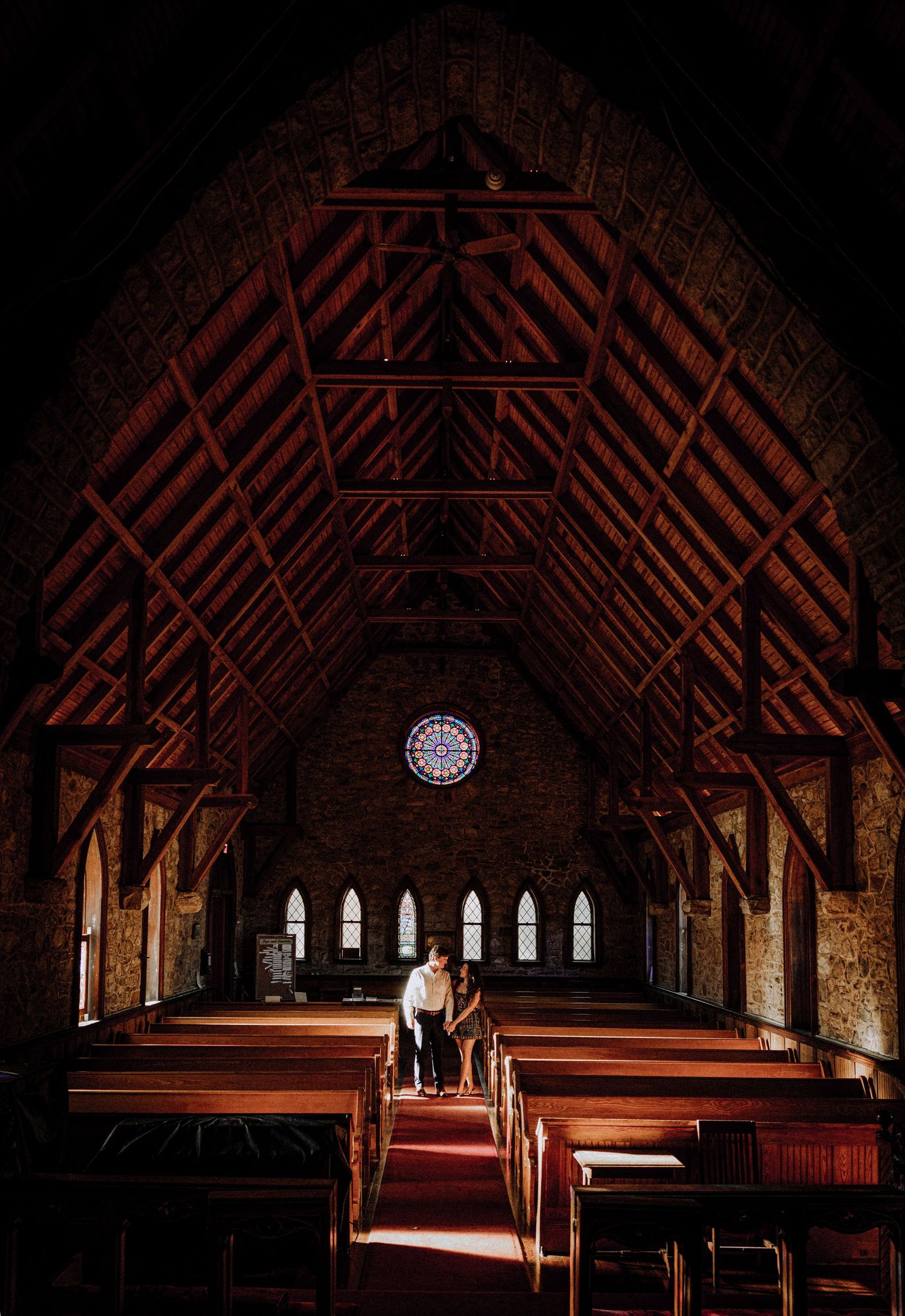 A historic church interior with wooden beams and arched windows.