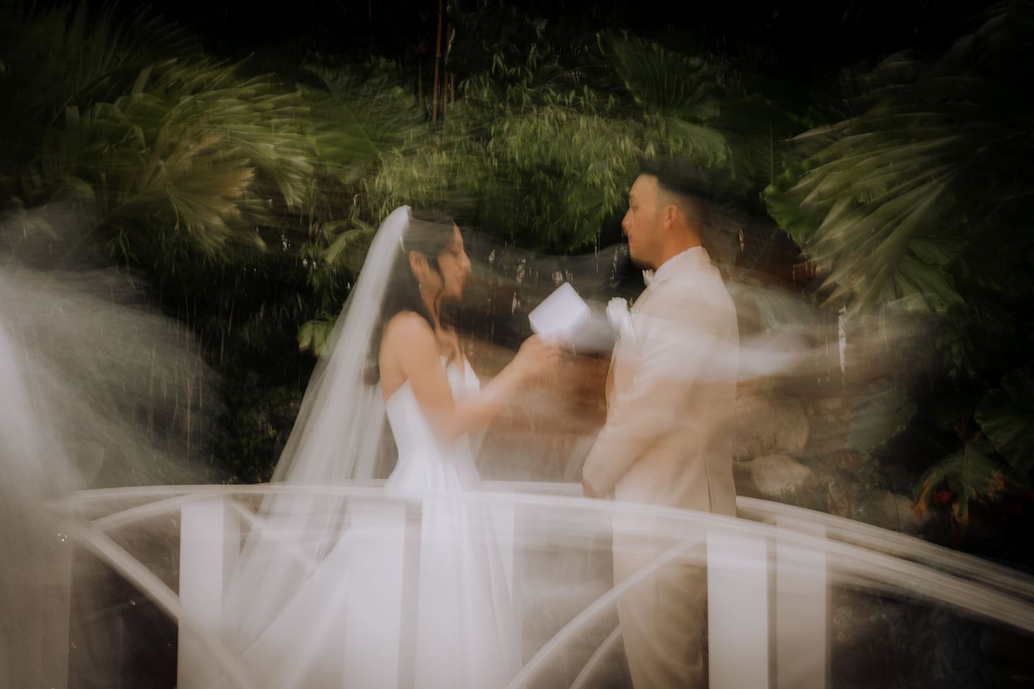Romantic wedding couple embraces under palm trees during a sunset photoshoot.