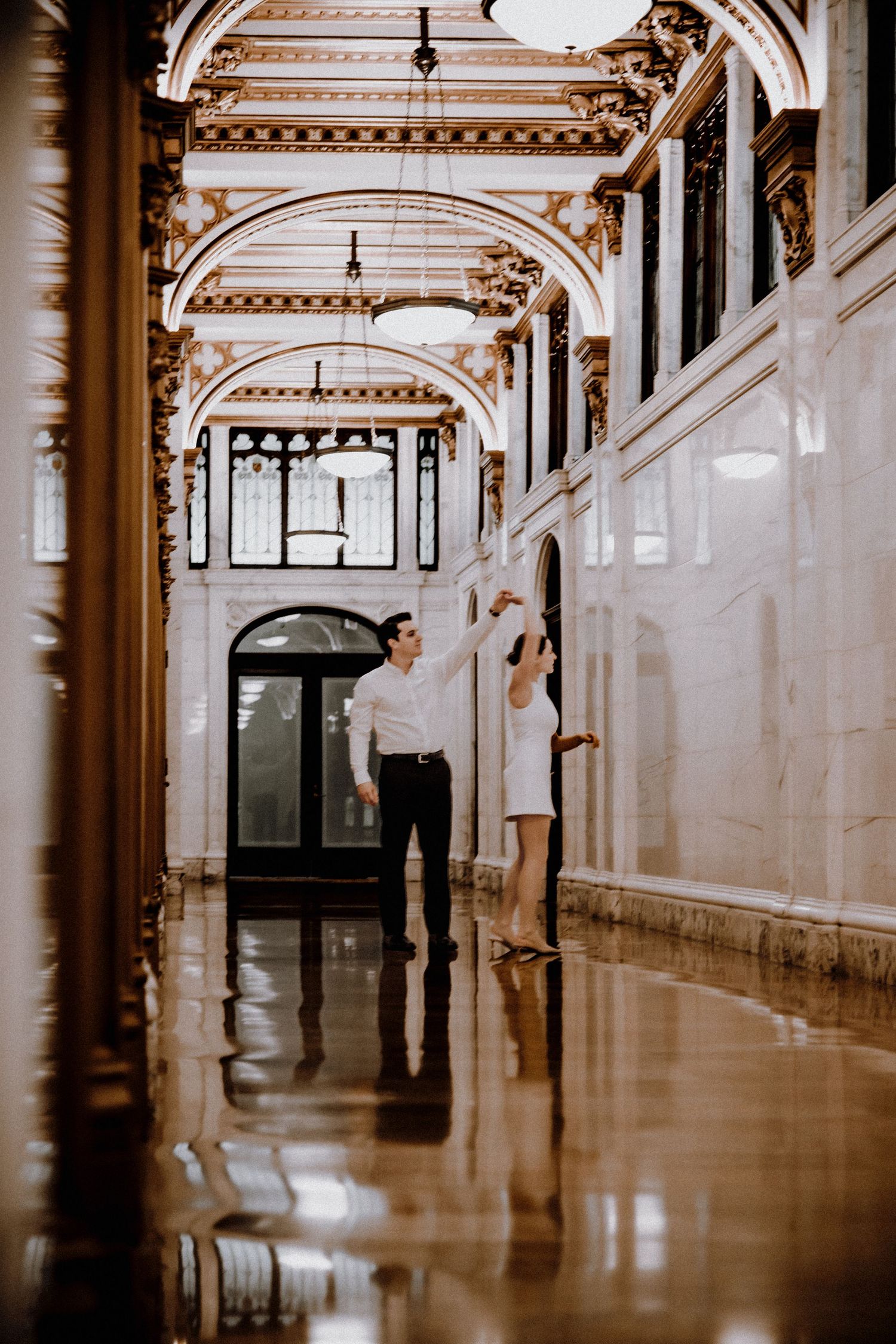 Long ornate corridor with arched ceilings and polished floors in a historic building.