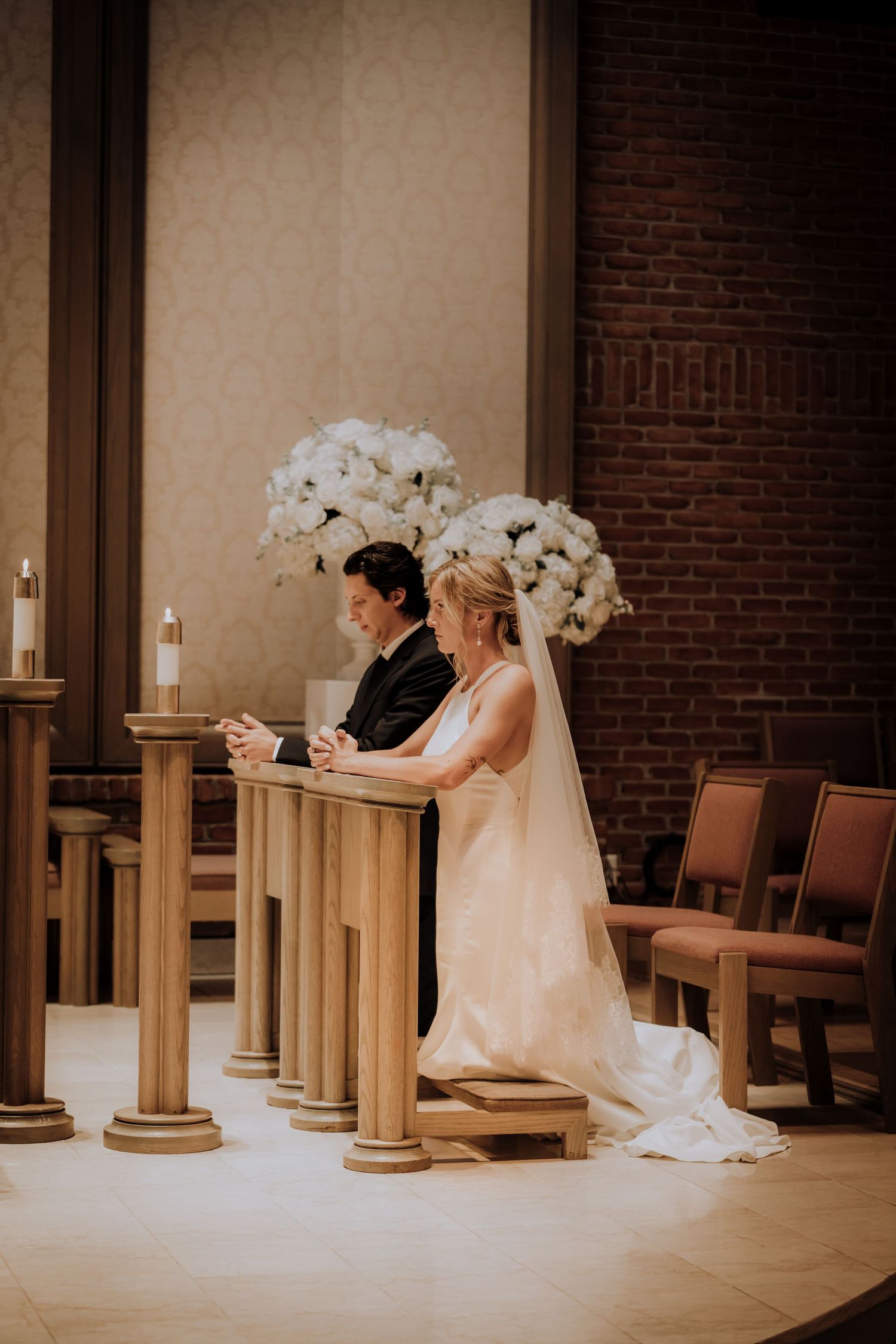 Wedding ceremony setting with white orchid arrangements and wooden church pews.