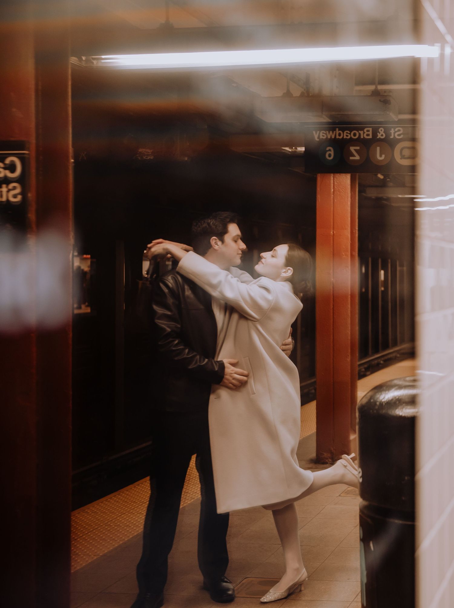 Couple embracing in a dimly lit subway station hallway.