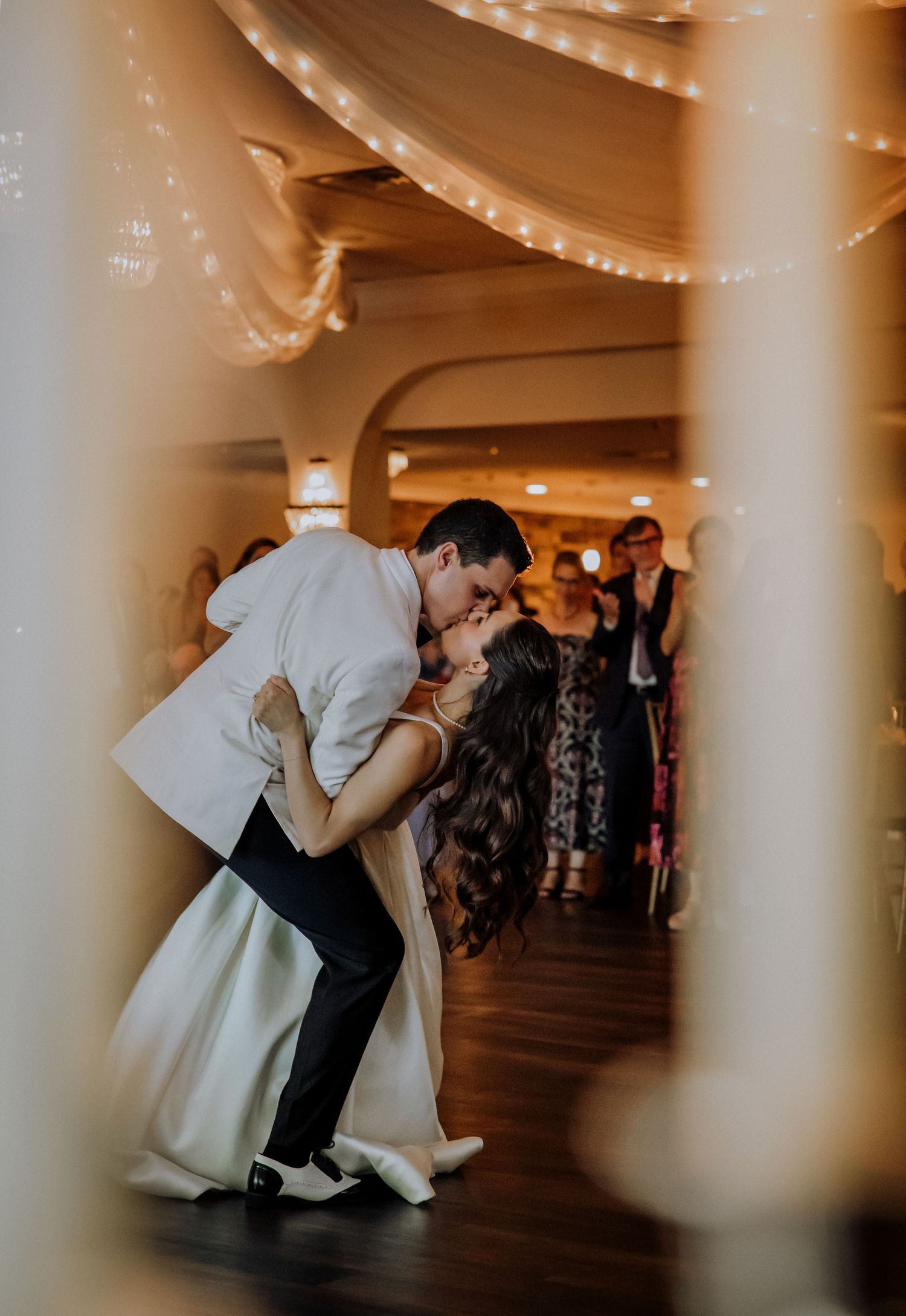 Bride and groom share a romantic dip kiss on the dance floor at their elegant wedding reception.Editorial and Cinematic Wedding photos
