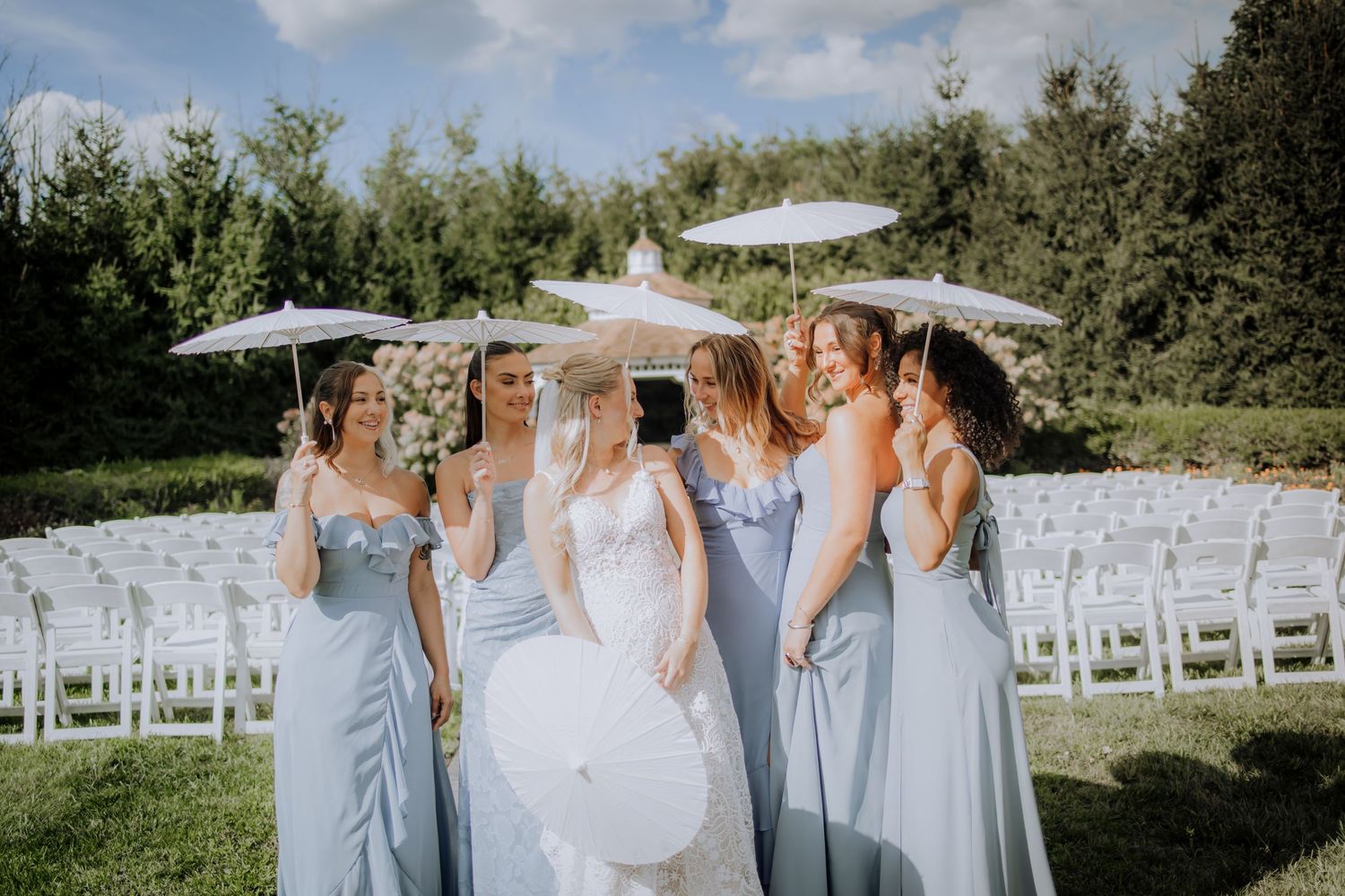 Wedding ceremony setup with white chairs and umbrellas under blue summer sky.Editorial and Cinematic Wedding photos