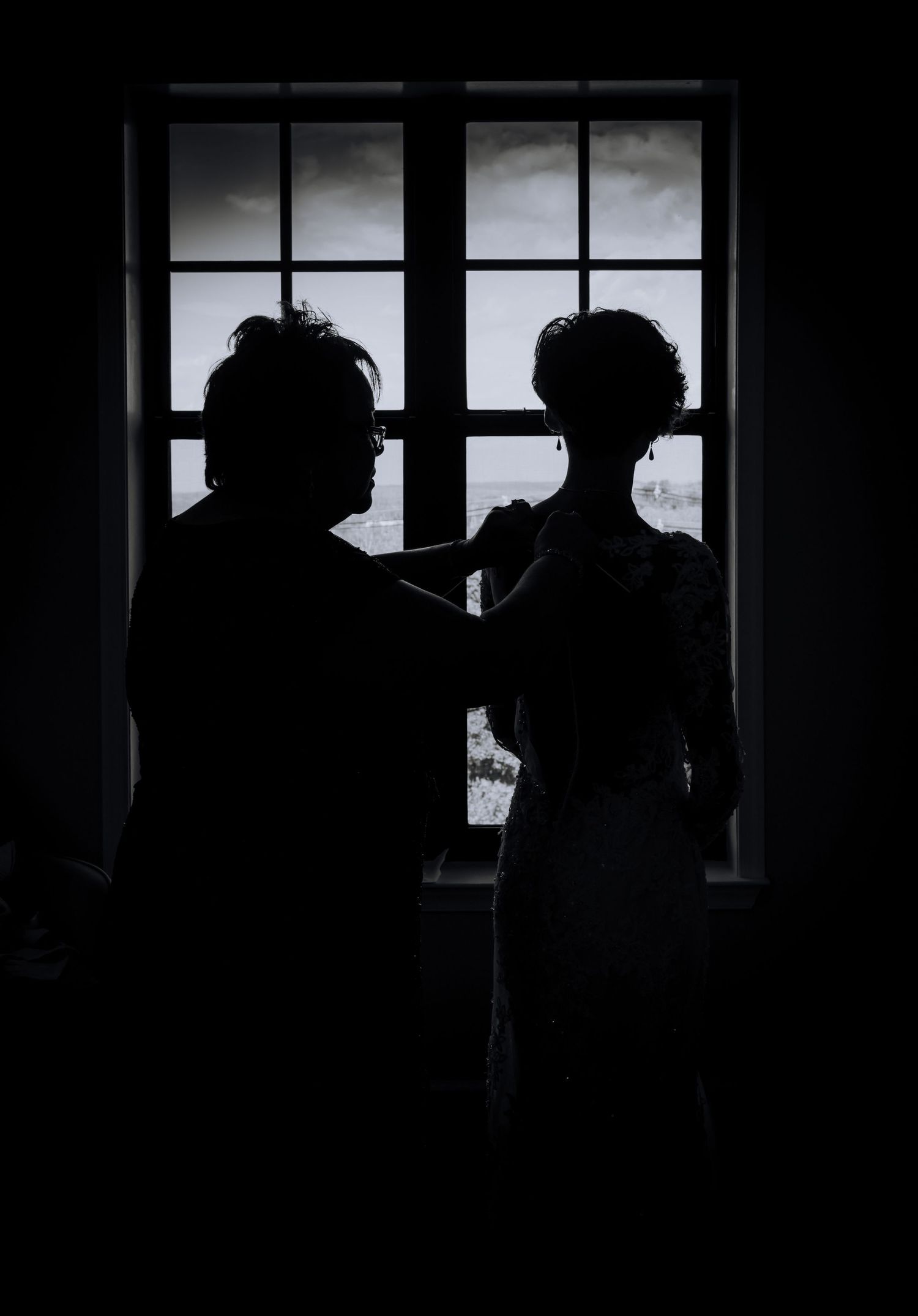 Silhouettes against window light creating dramatic wedding day portraits.
