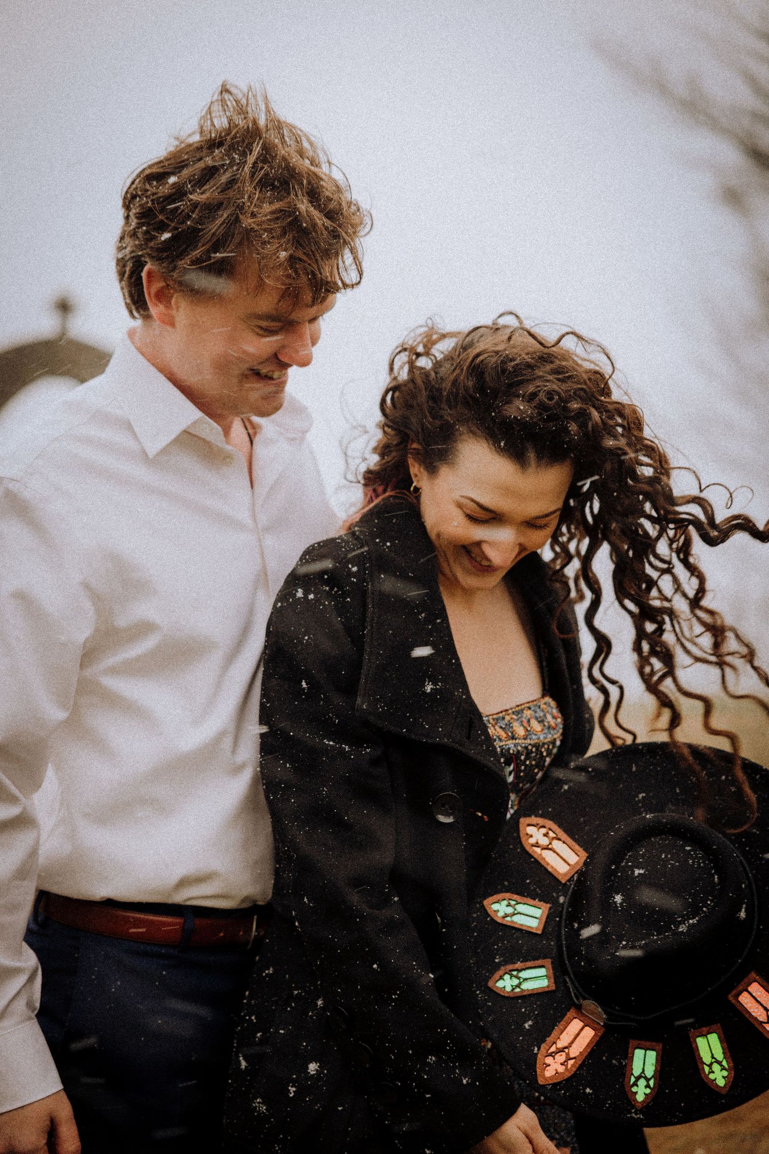 A couple shares joyful moments outdoors while wearing contrasting black and white outfits.