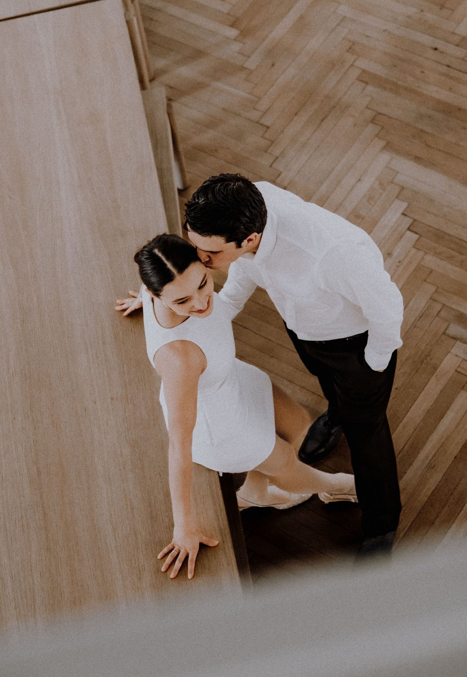 Artistic overhead shot of couple on herringbone wood flooring in historic building.