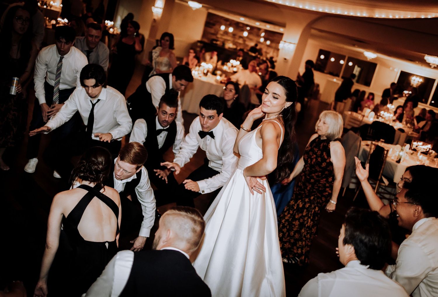 Bride in white gown dancing joyfully with guests at elegant wedding reception party.Editorial and Cinematic Wedding photos
