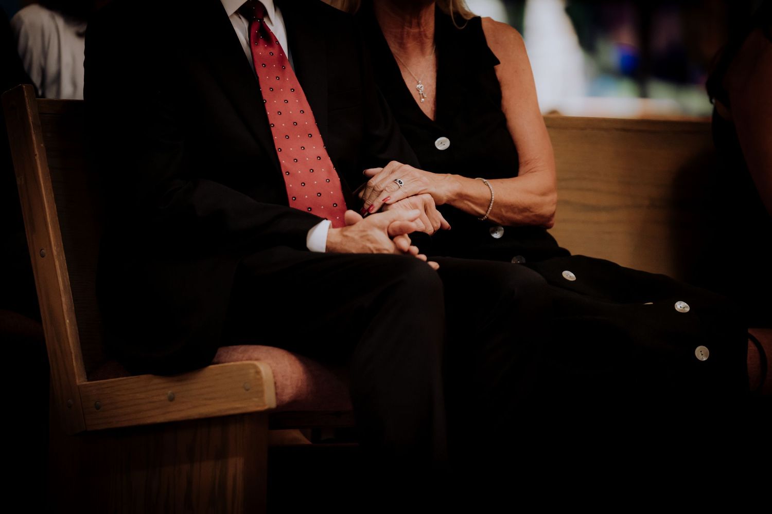 Close-up of clasped hands during an intimate moment at a wedding ceremony.
