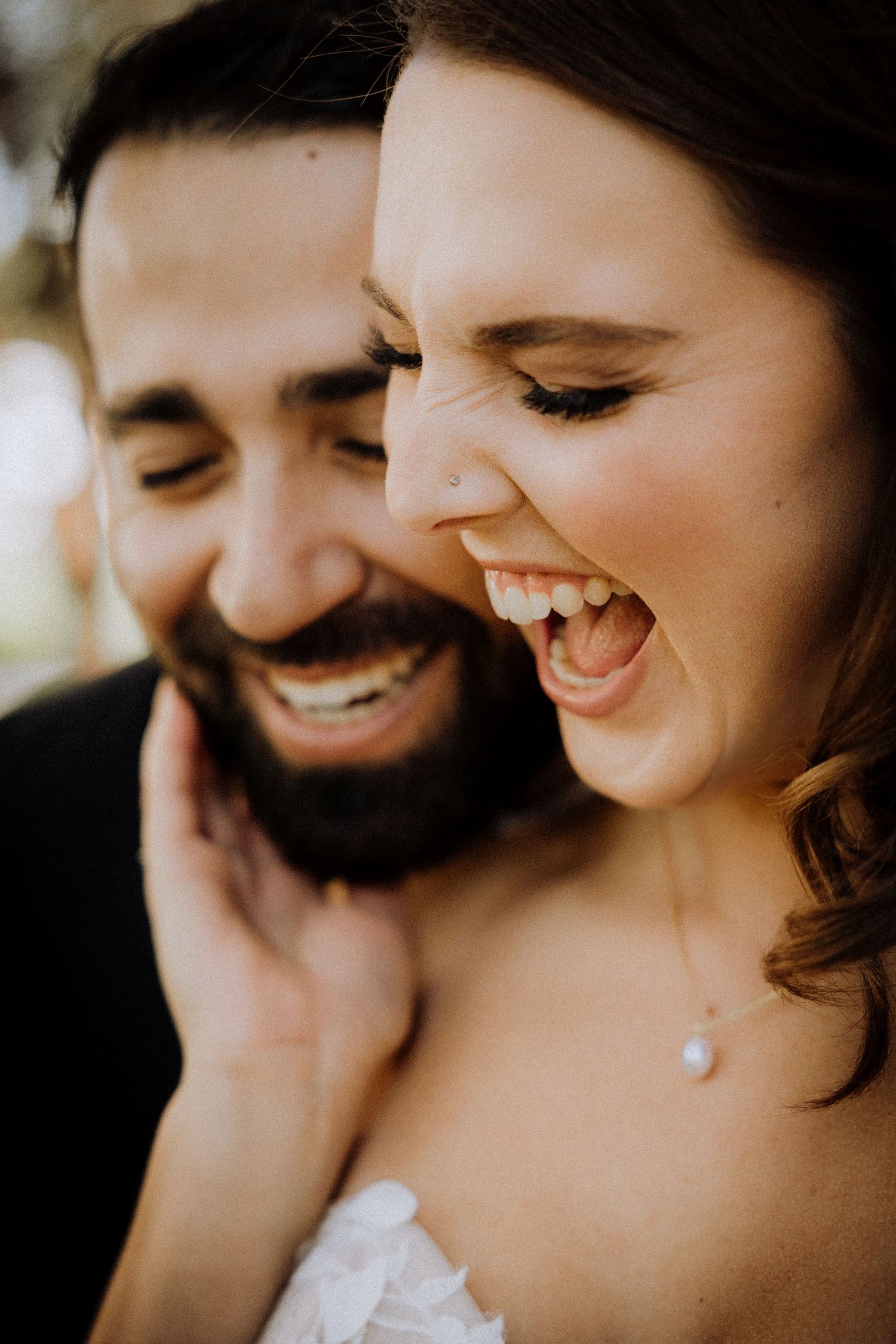 Close-up candid shot of joyful laughter and genuine emotion during wedding portraits.