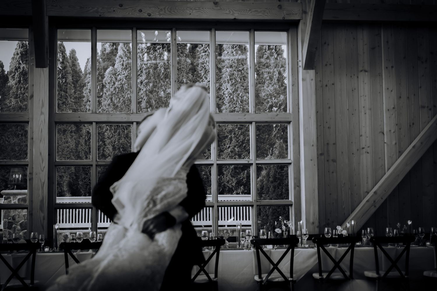 Artistic black and white photo of flowing wedding dress against large venue windows.Editorial and Cinematic Wedding photos