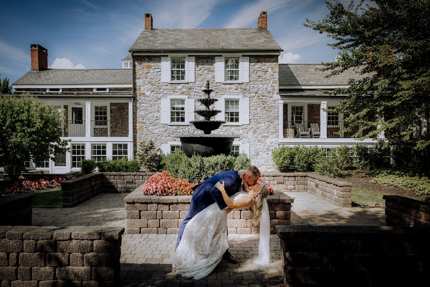 Romantic dip pose in front of a historic stone mansion with manicured gardens.Editorial and Cinematic Wedding photos