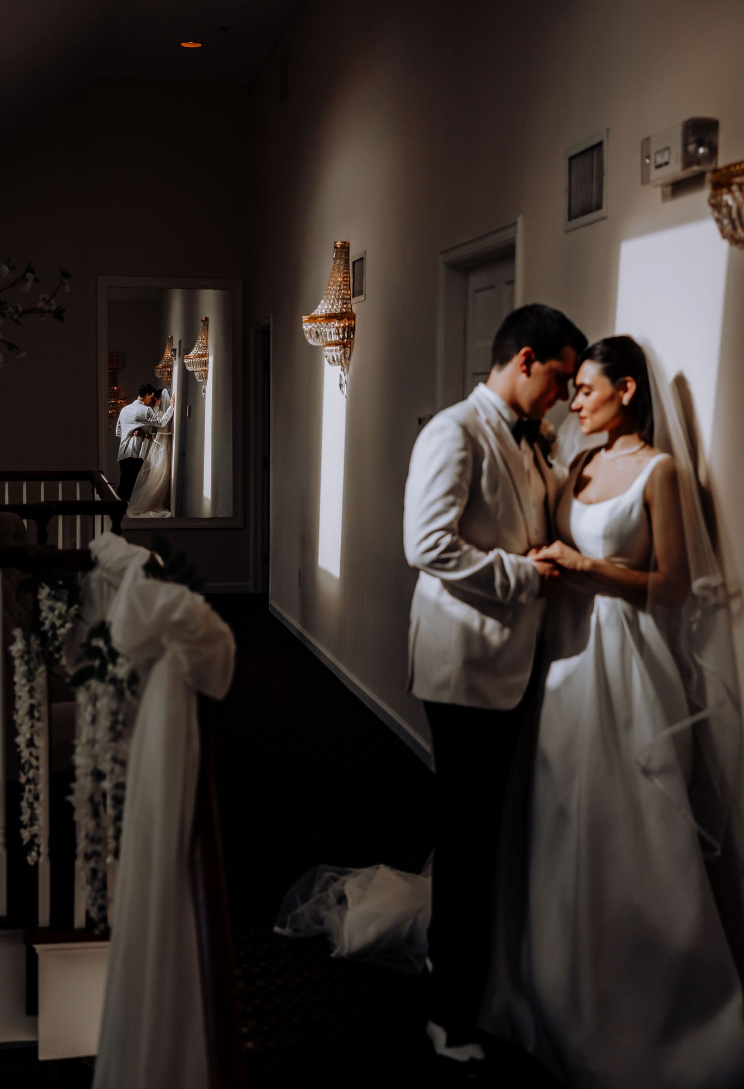 Artistic black and white sequence of a couple in white attire dancing in a dim room.