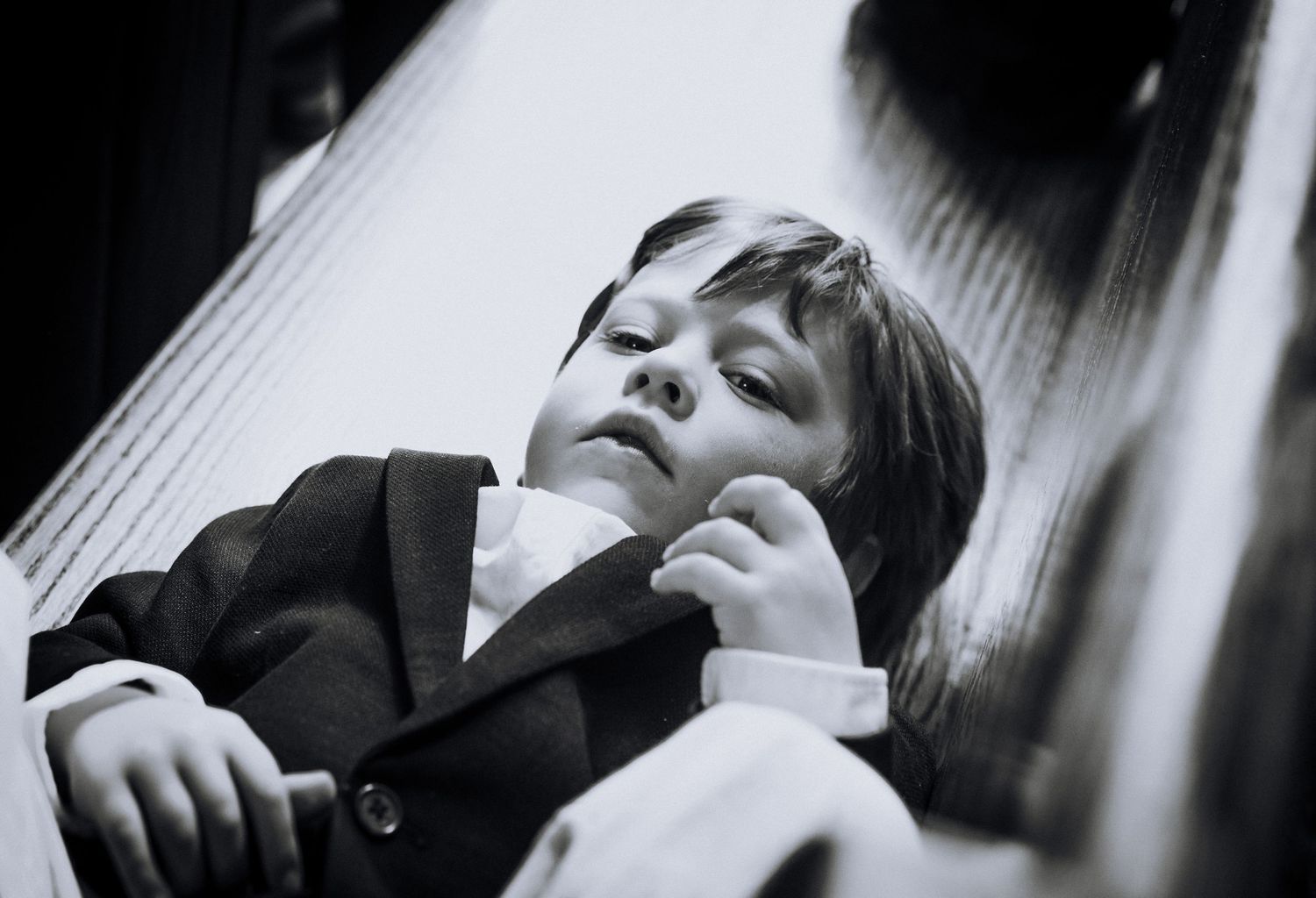 Black and white photo of a young boy in a suit looking upward with a thoughtful expression.