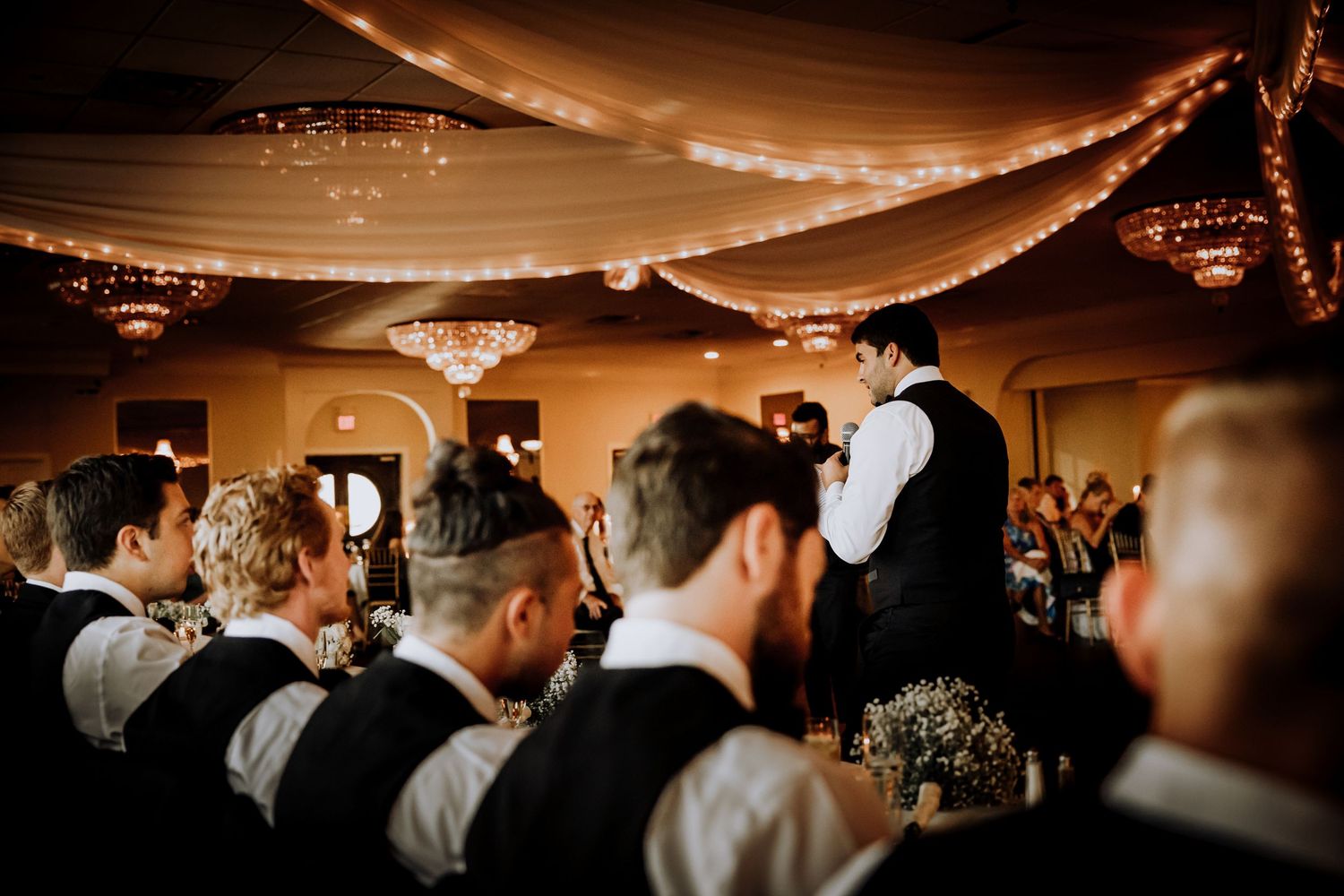 Wedding reception guests gathered in a dimly lit ballroom.