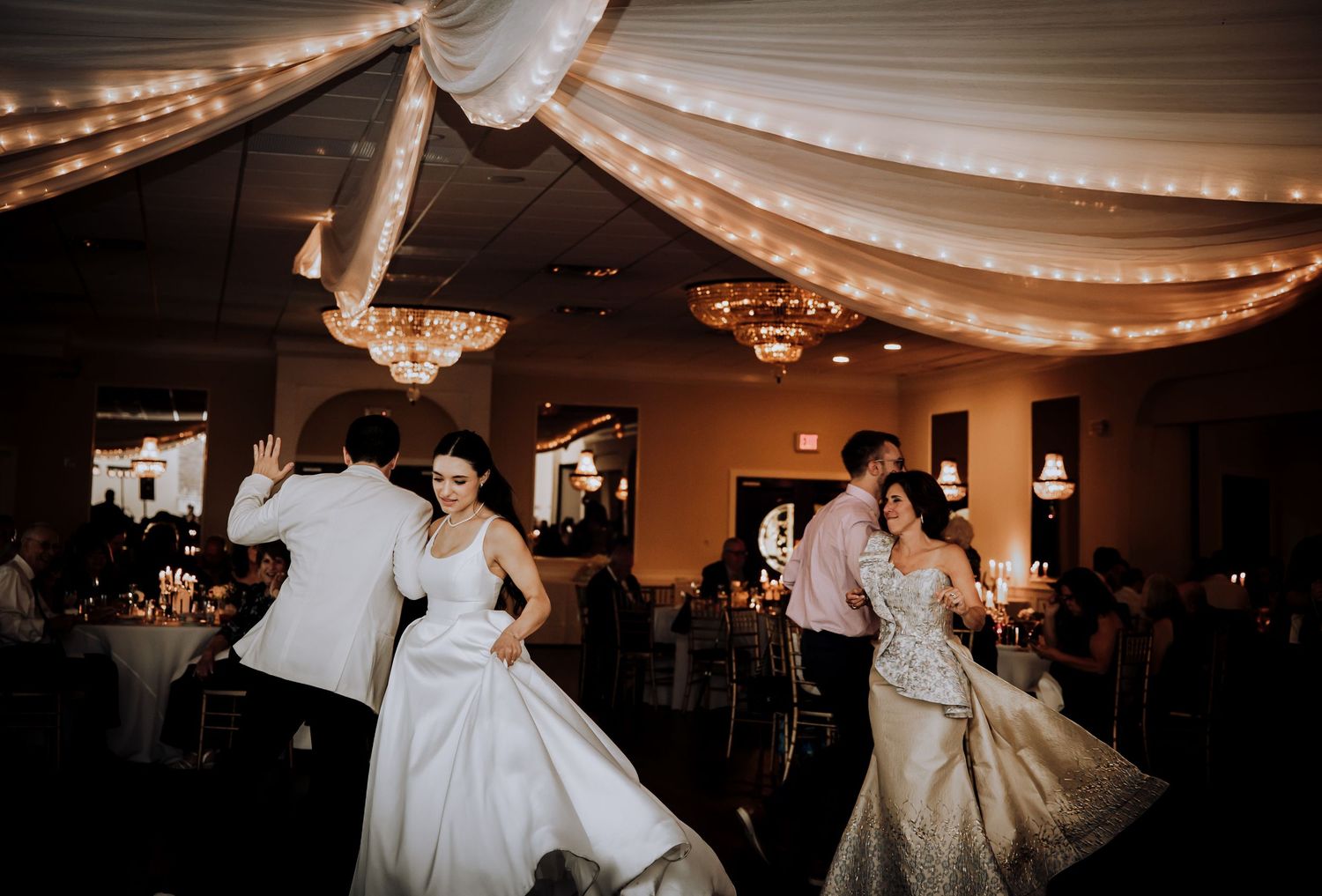 Wedding reception dance floor illuminated with warm string lights and elegant decor.