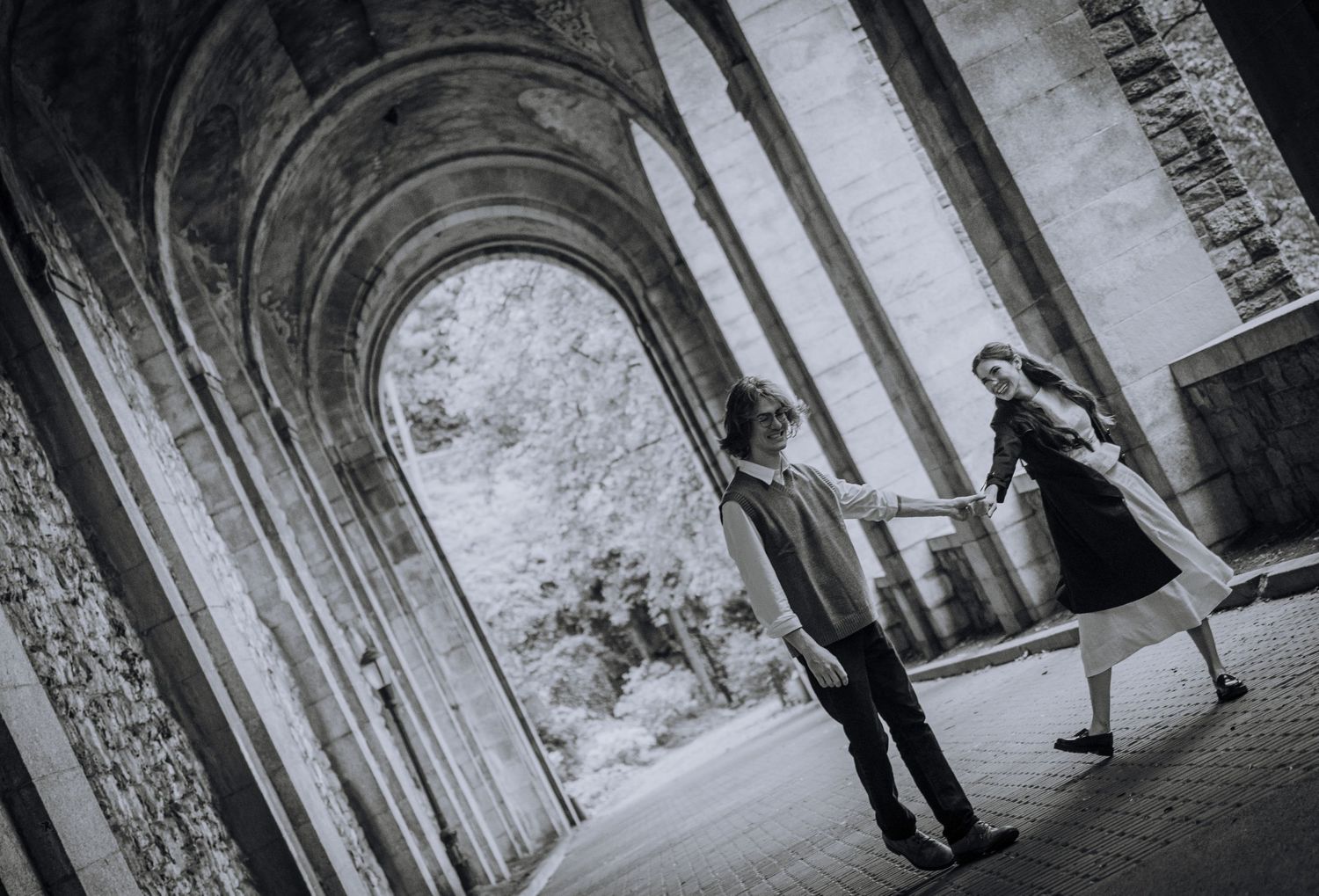 A couple stands in silhouette under a dramatic stone archway.