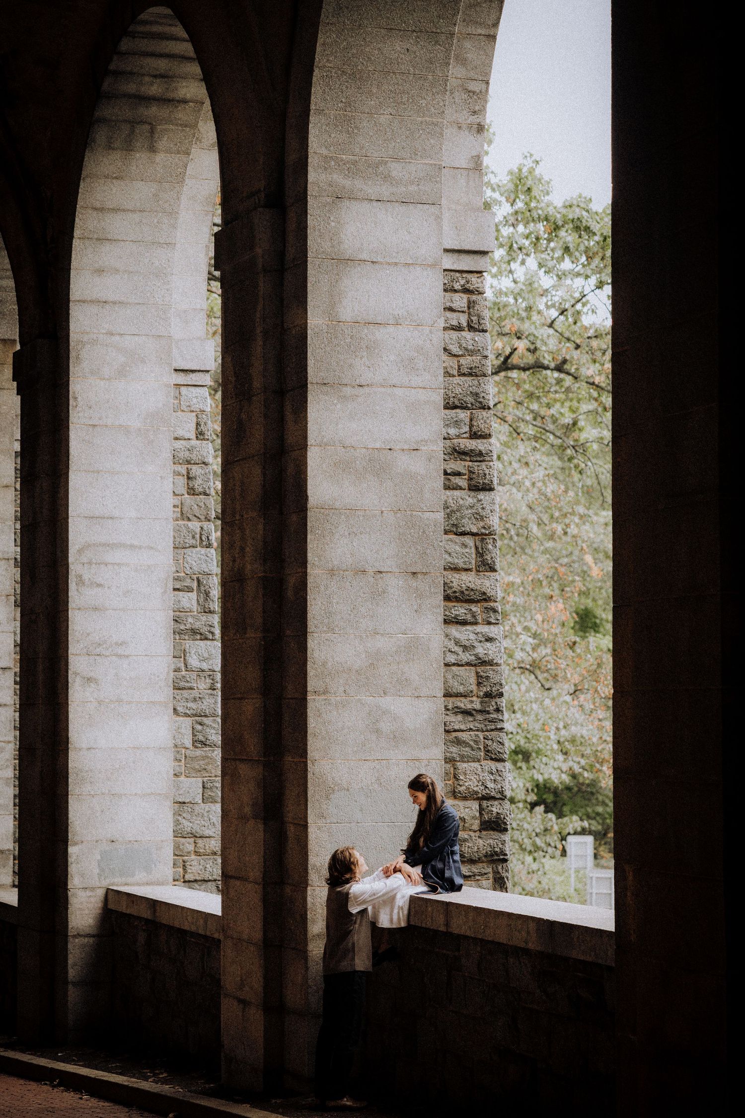 Silhouettes of two people framed by dramatic stone archways and natural light.