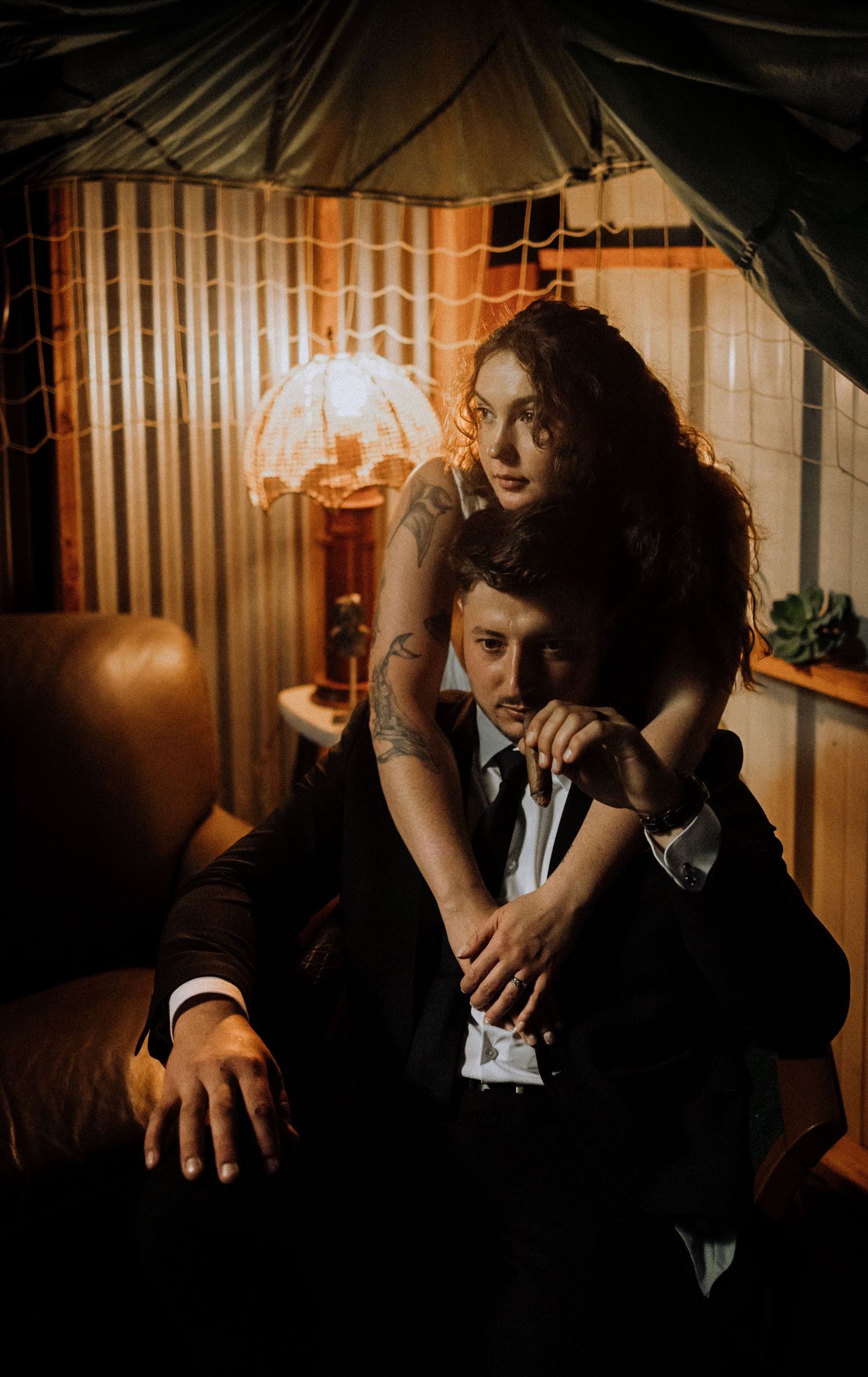 Intimate couple portrait session with moody lighting and dark fabric backdrop.