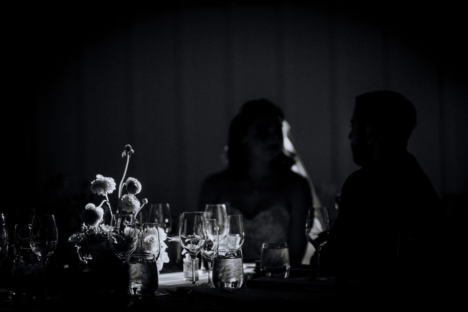 Dark and moody reception table setting with ambient lighting and glassware.