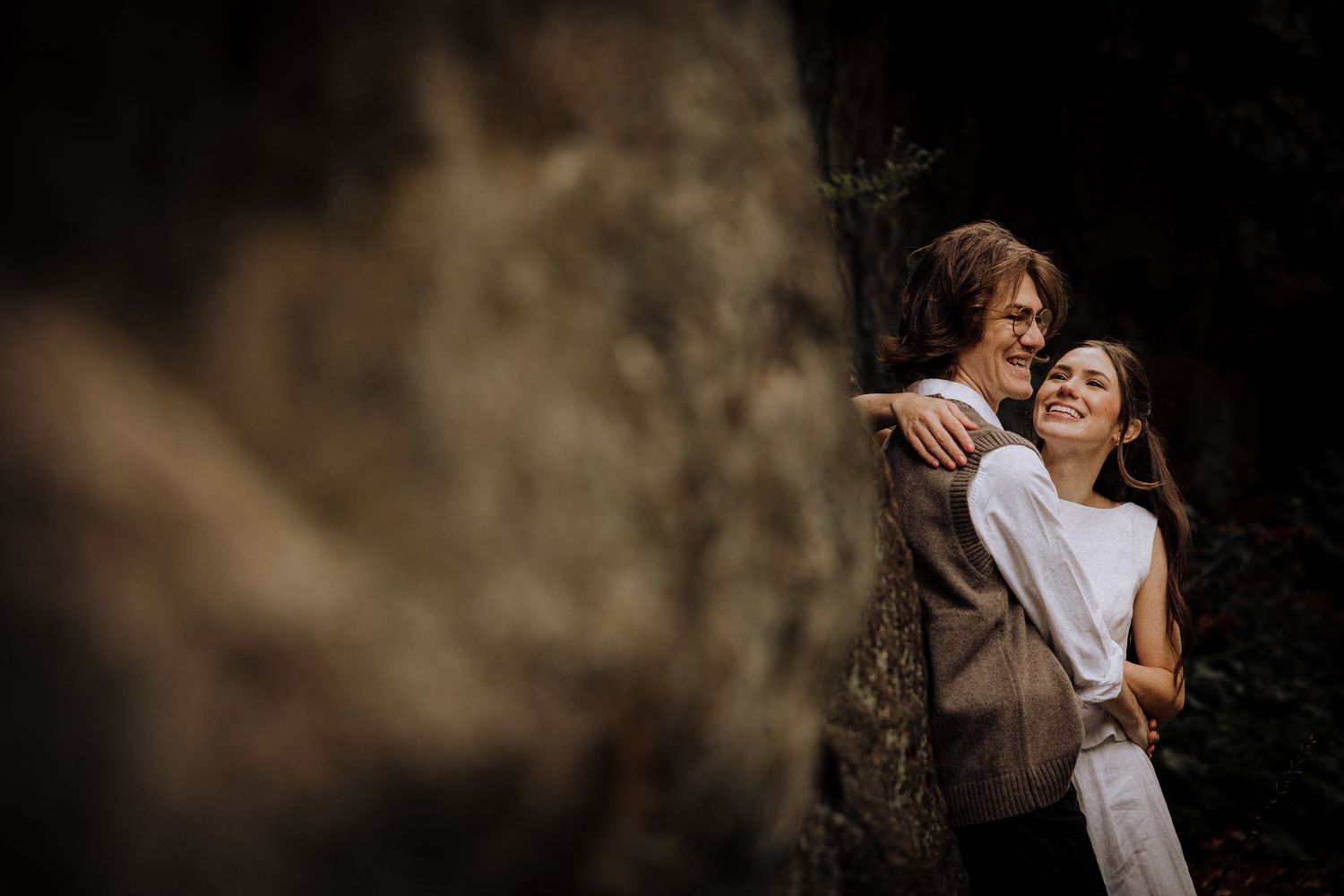 Intimate moment captured in moody lighting with natural elements.