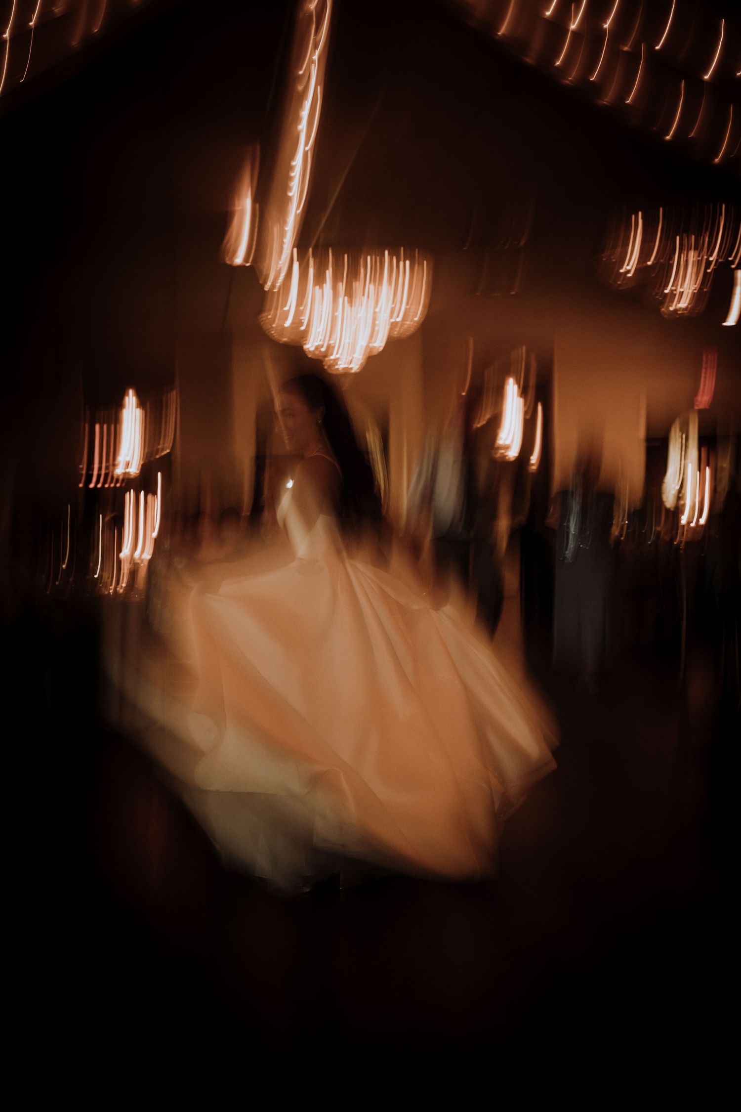 Abstract motion blur of dancers in formal attire at a wedding reception.