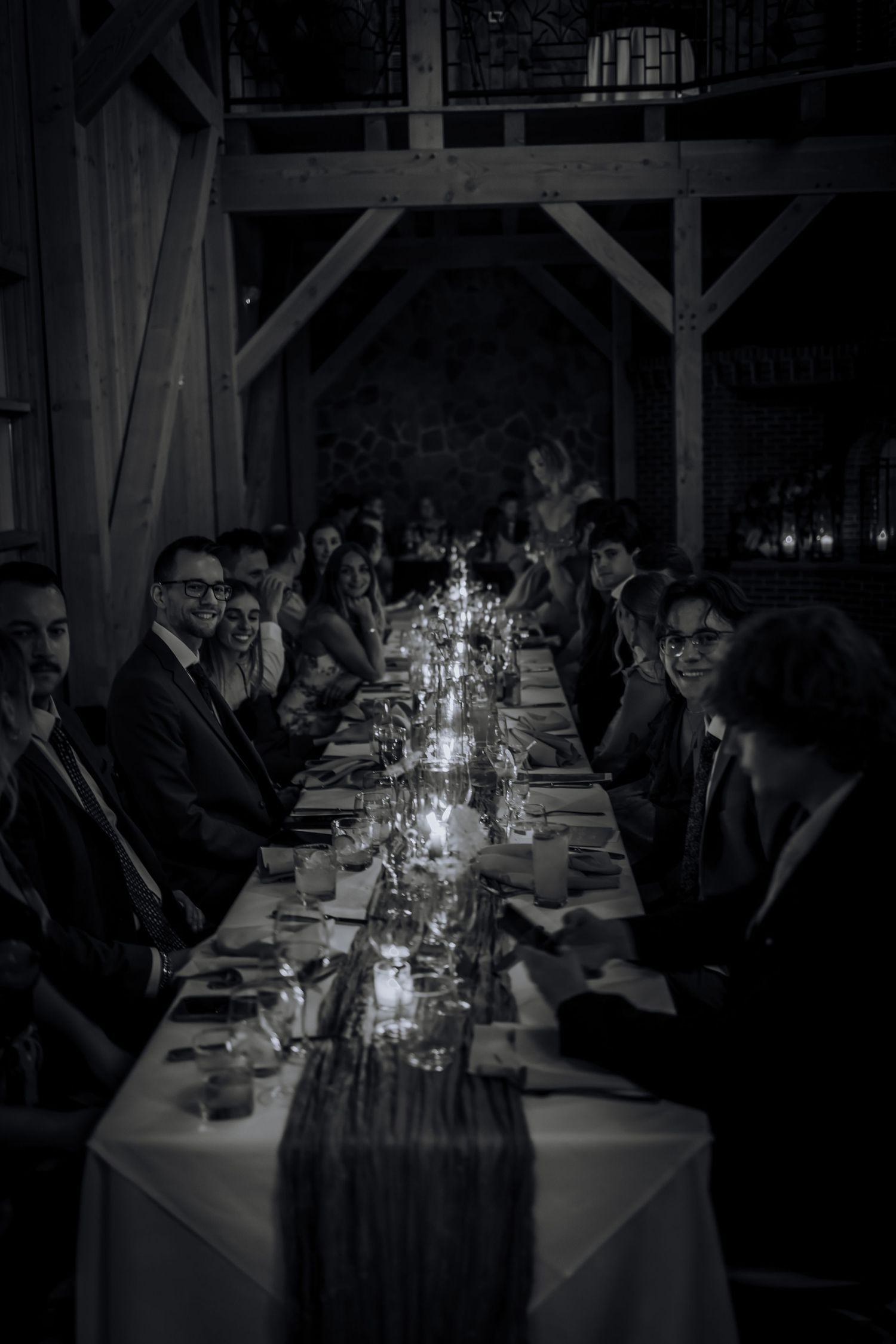 Long reception tables set with glowing candles in a rustic barn venue.