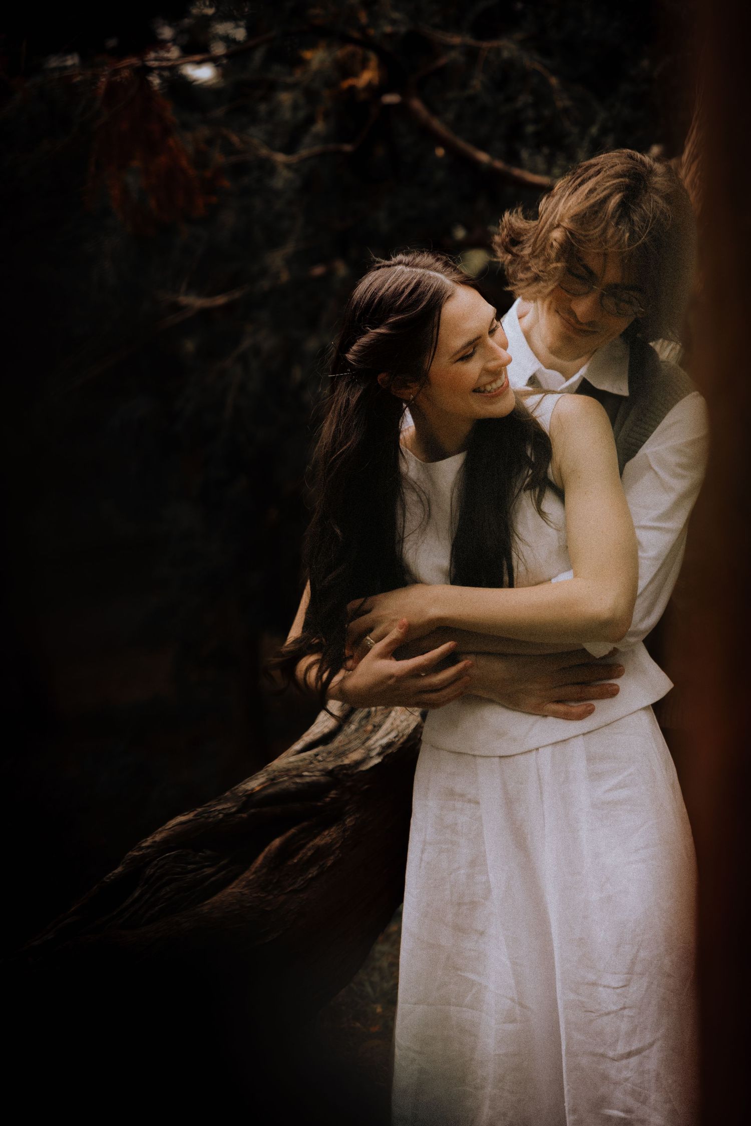 Romantic moment shared between two people in white against a dark background.