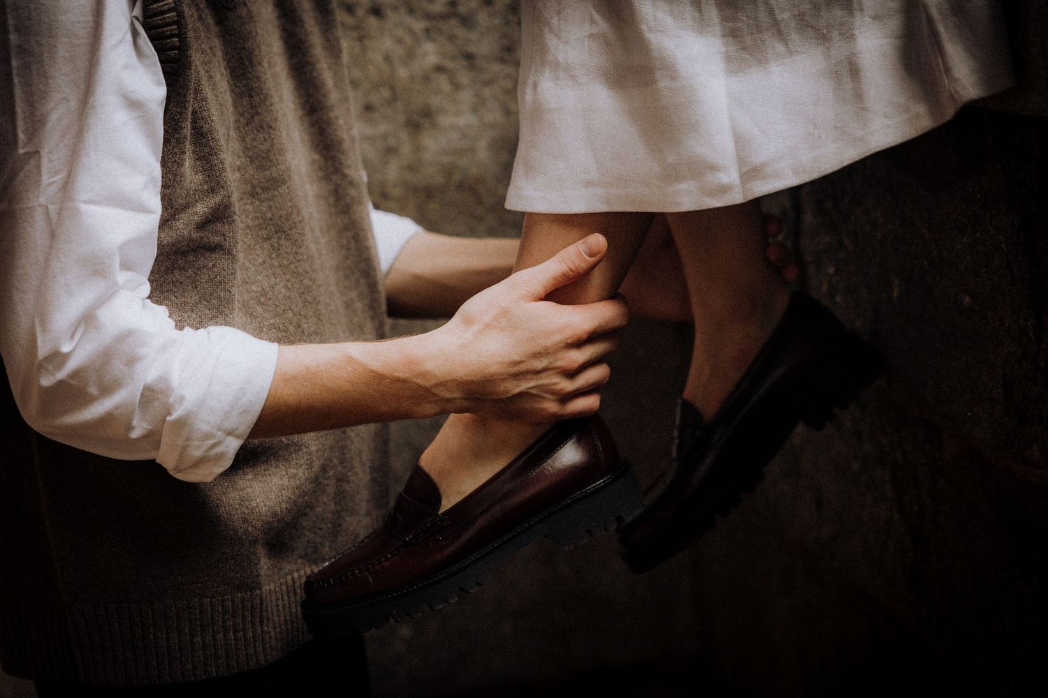 Close-up details of hands and clothing in an intimate moment.