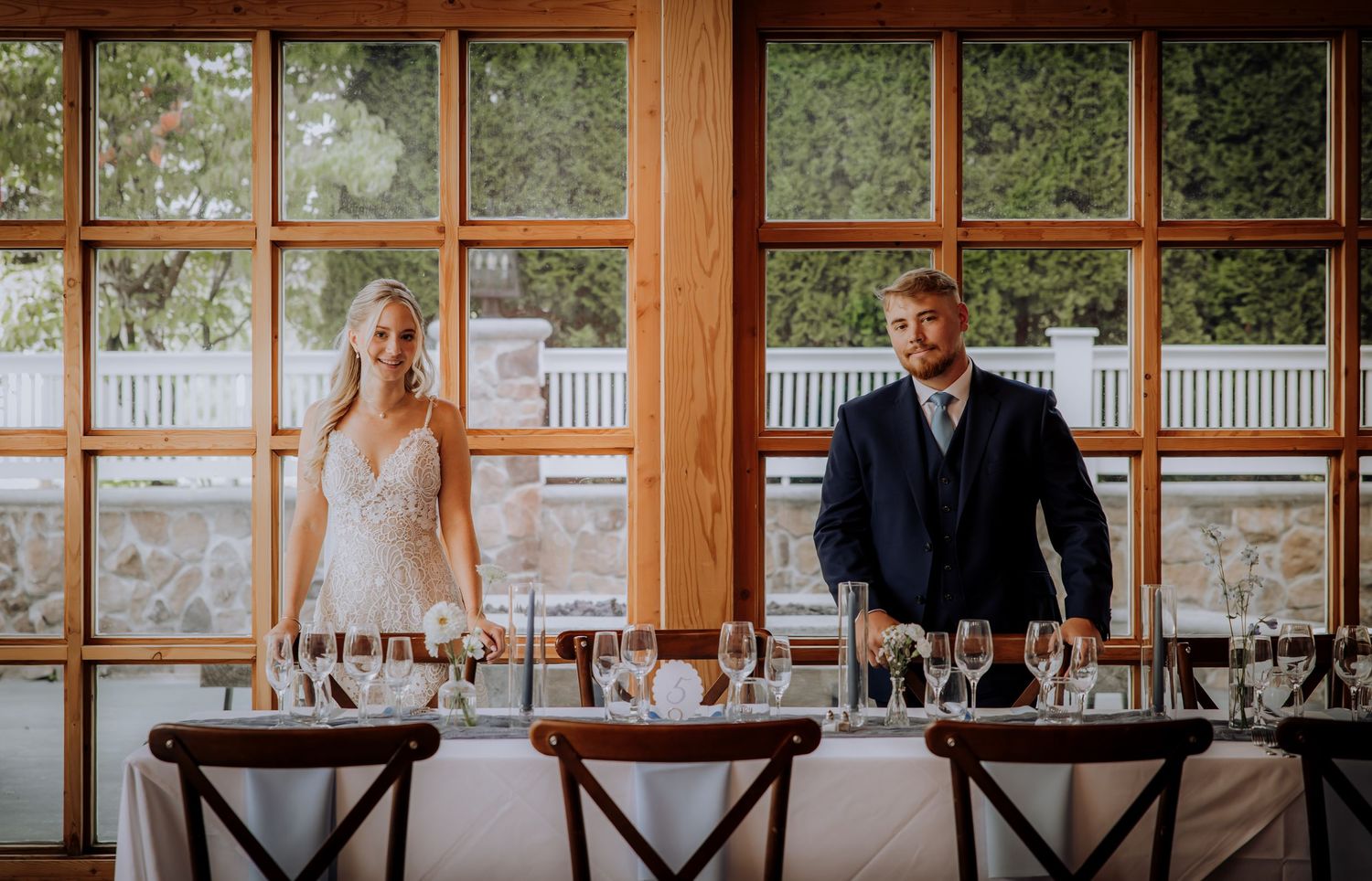 Wedding reception setup with elegant place settings and large windows in wooden venue.Editorial and Cinematic Wedding photos