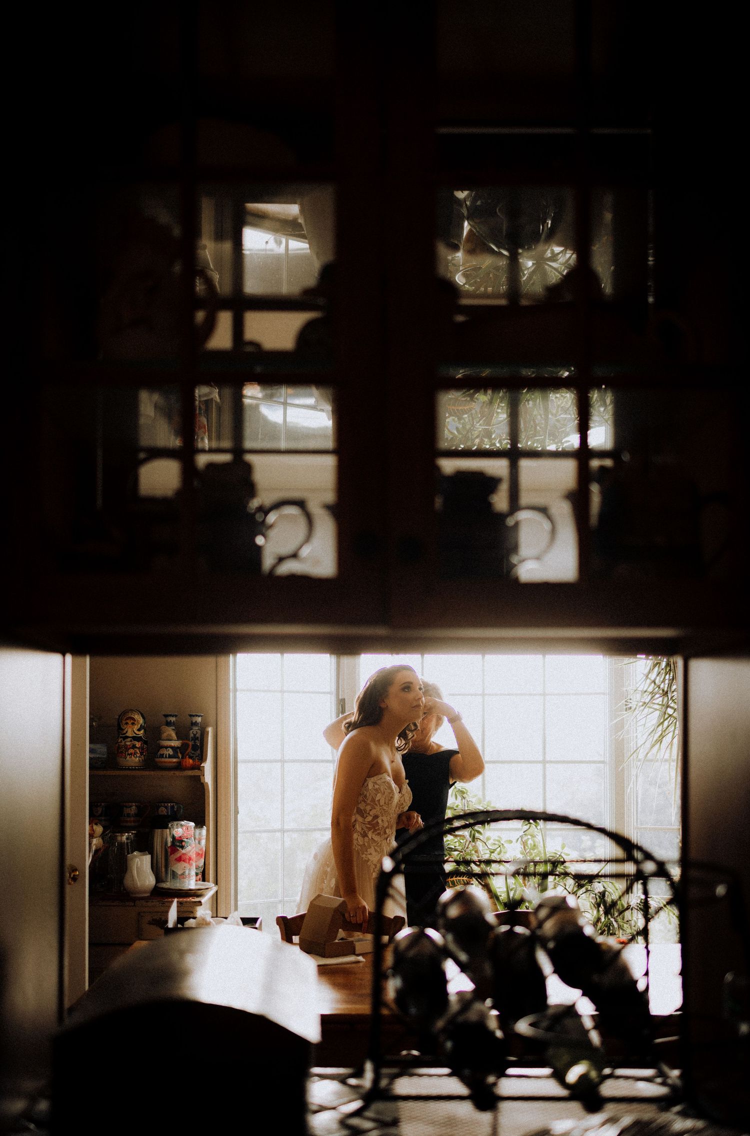 Silhouettes of people working in a dimly lit kitchen with backlit windows.