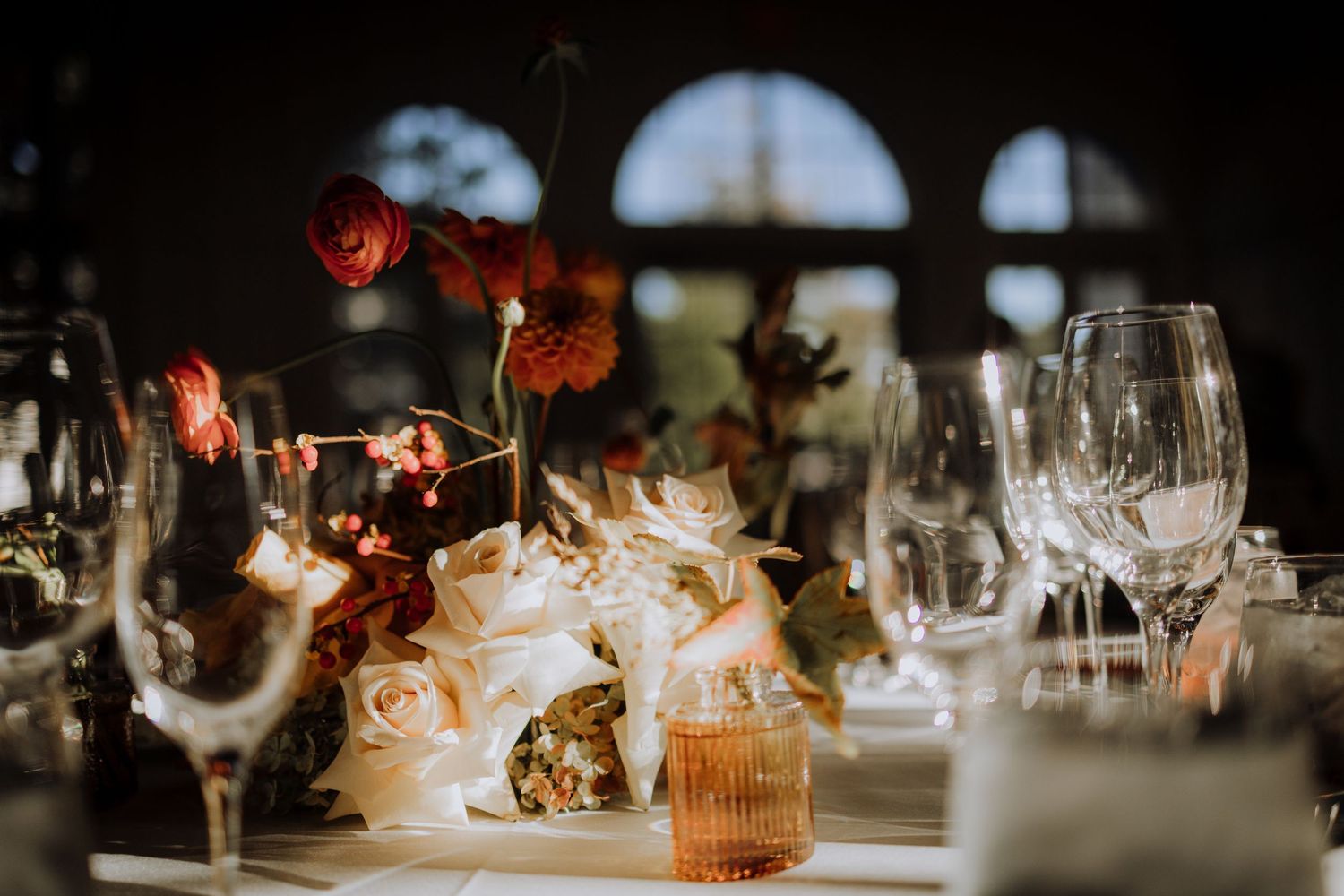 Elegant table setting with glassware and floral centerpieces at wedding reception.