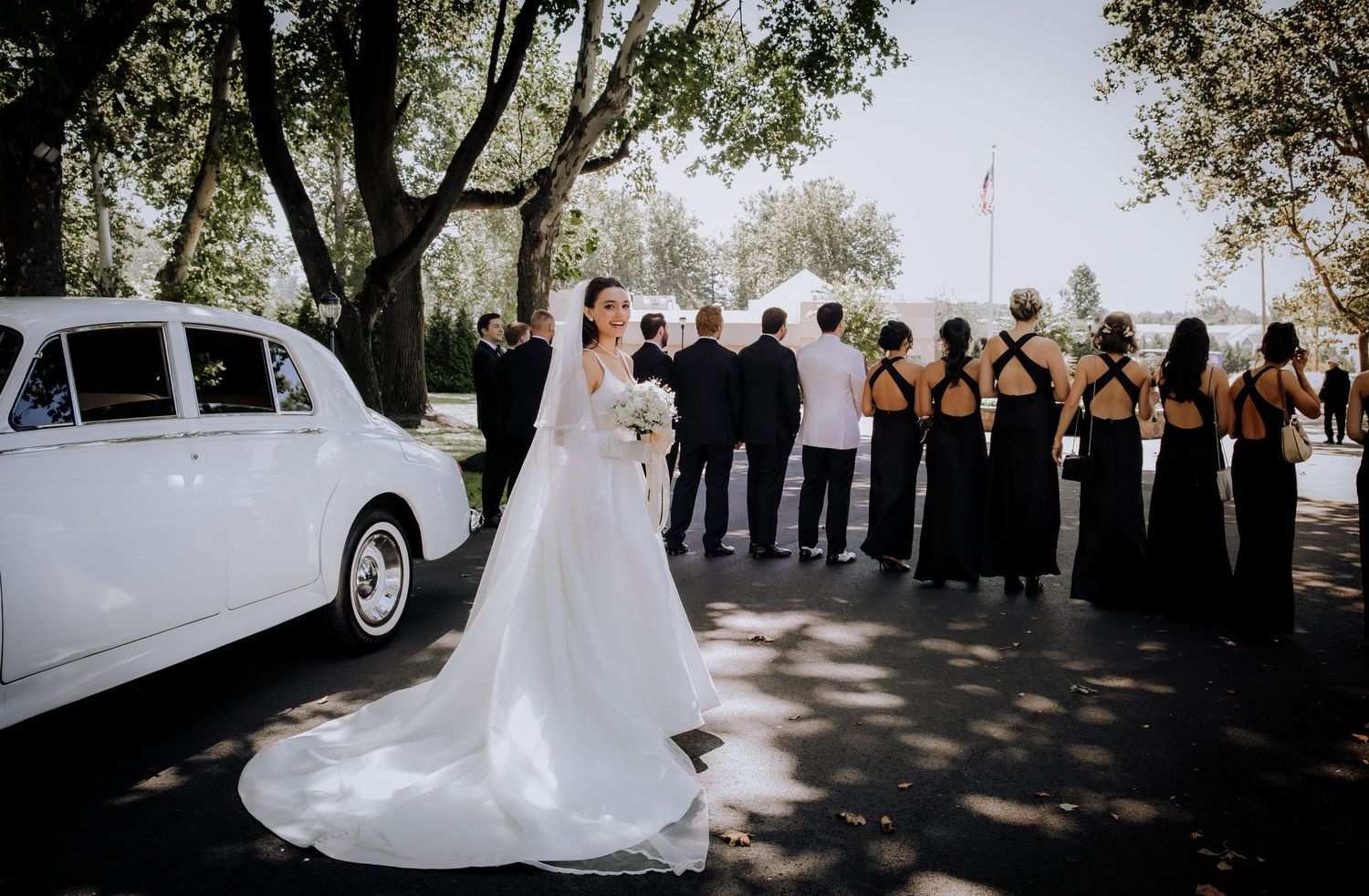 Panoramic view of an outdoor wedding ceremony with guests and a white vintage car.