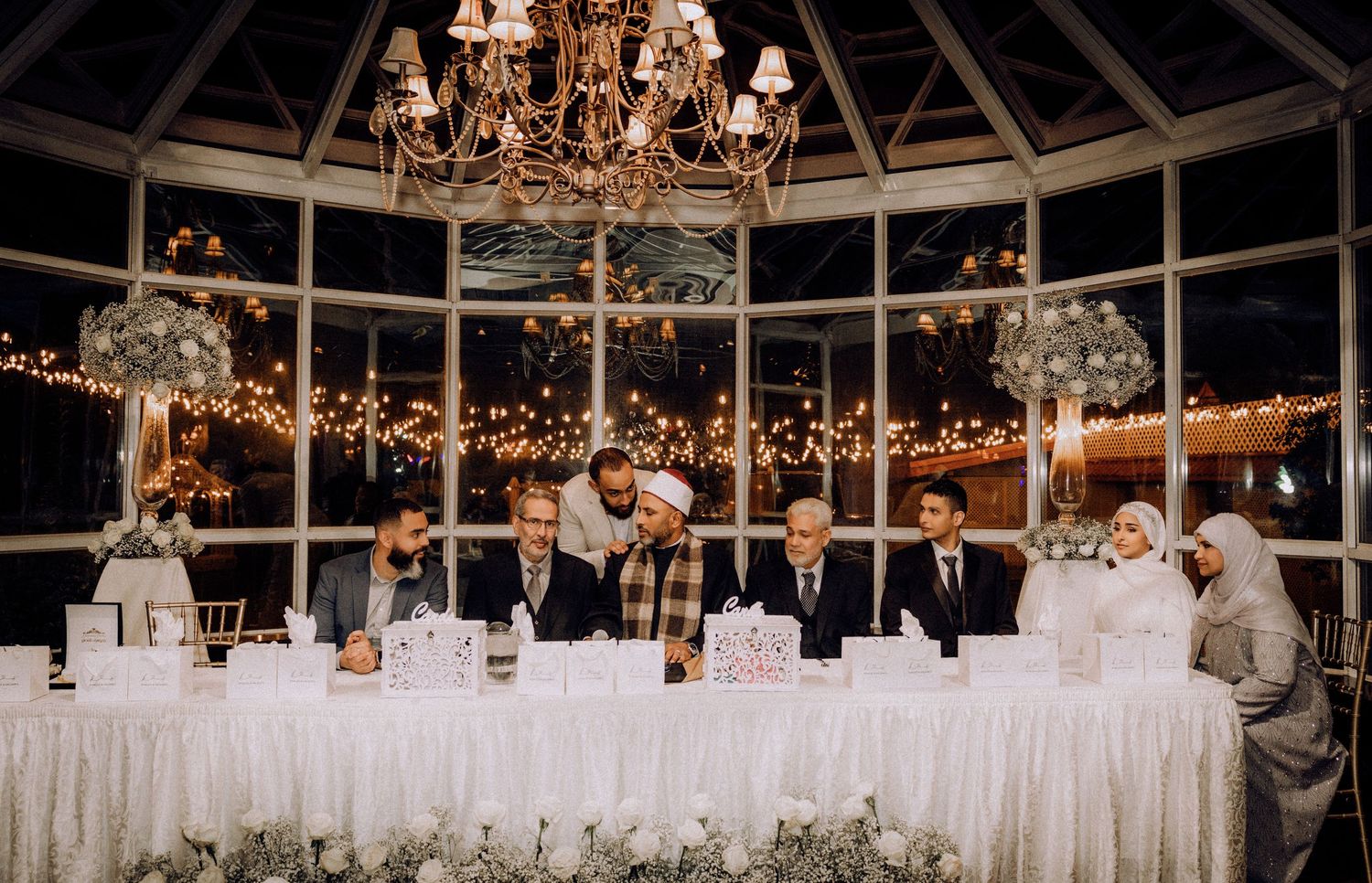 Elegant wedding reception venue with crystal chandeliers and white draping in a glass-domed ceiling.
